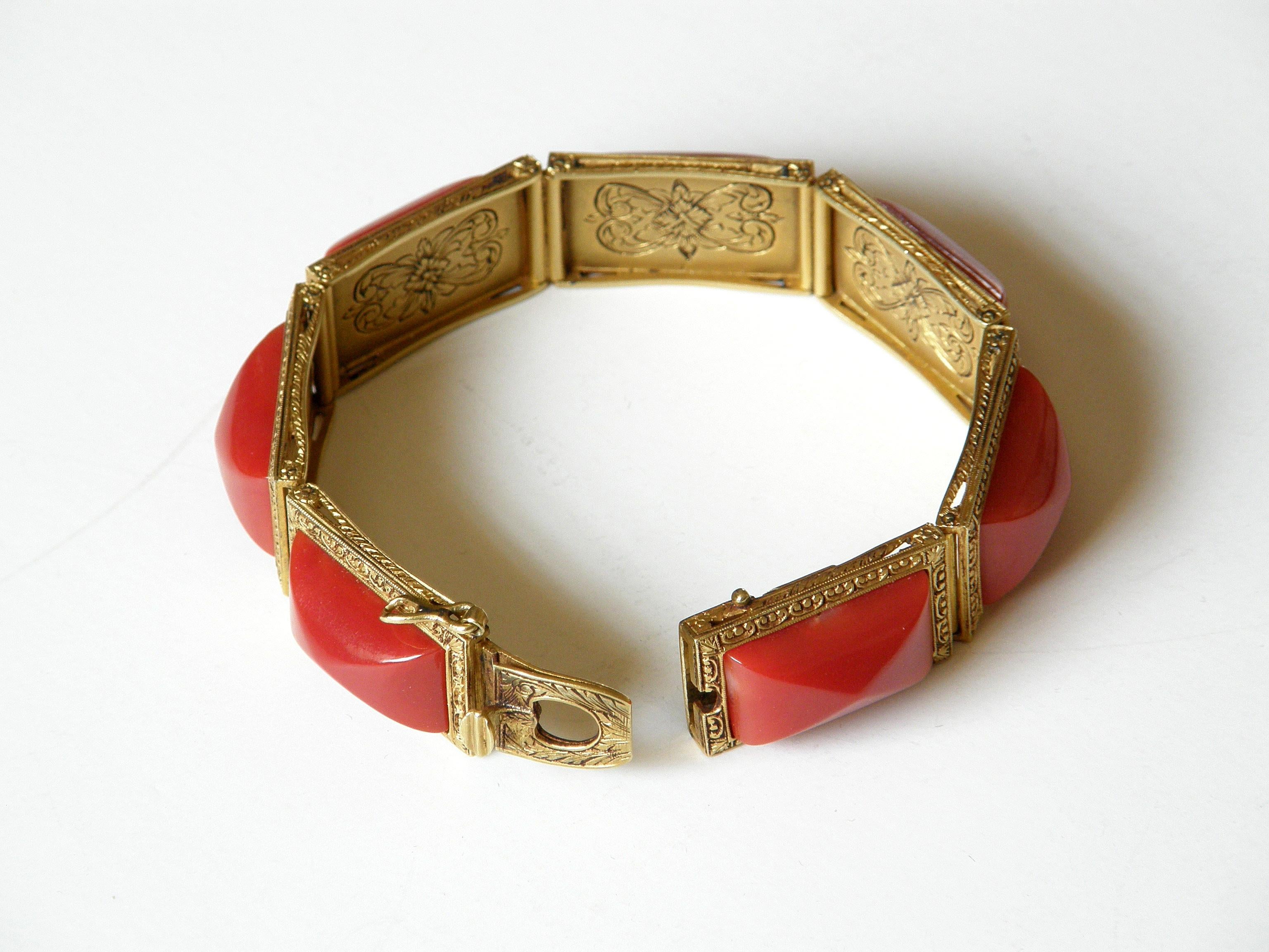 This handsome, gold link bracelet is beautifully detailed. Each link is set with a rectangular, pyramid cabochon stone. The stones are framed by a delicate, scrolling pattern in the gold. Each link has pierced, decorative side panels to add strength