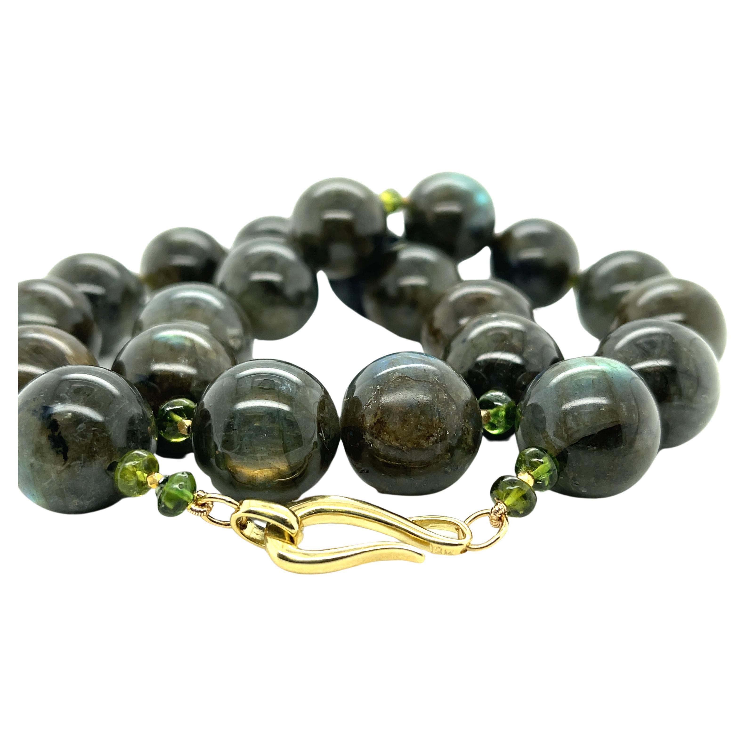 This eye-catching necklace features impressive 17mm round labradorite beads arranged with peridot beads and 18k yellow gold spaces for a unique look that can enhance many different outfits! The labradorite beads have a beautifully warm, earthy gray