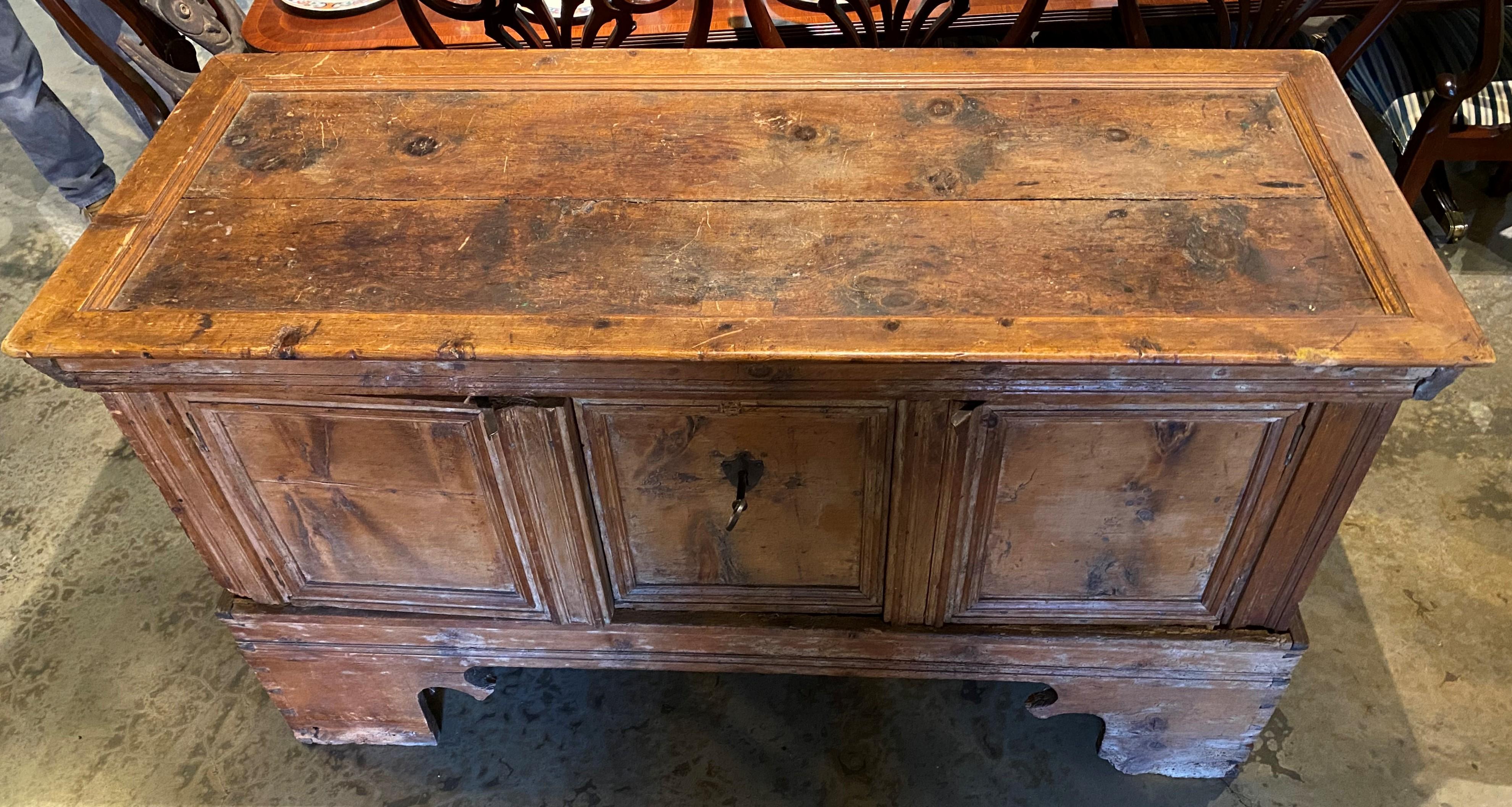 An interesting pine storage chest on frame, with molded panel top and front with old refinish, that has been retro-fitted to open through two of the front panels rather than with the lift top, which is now secured. The center panel contains an