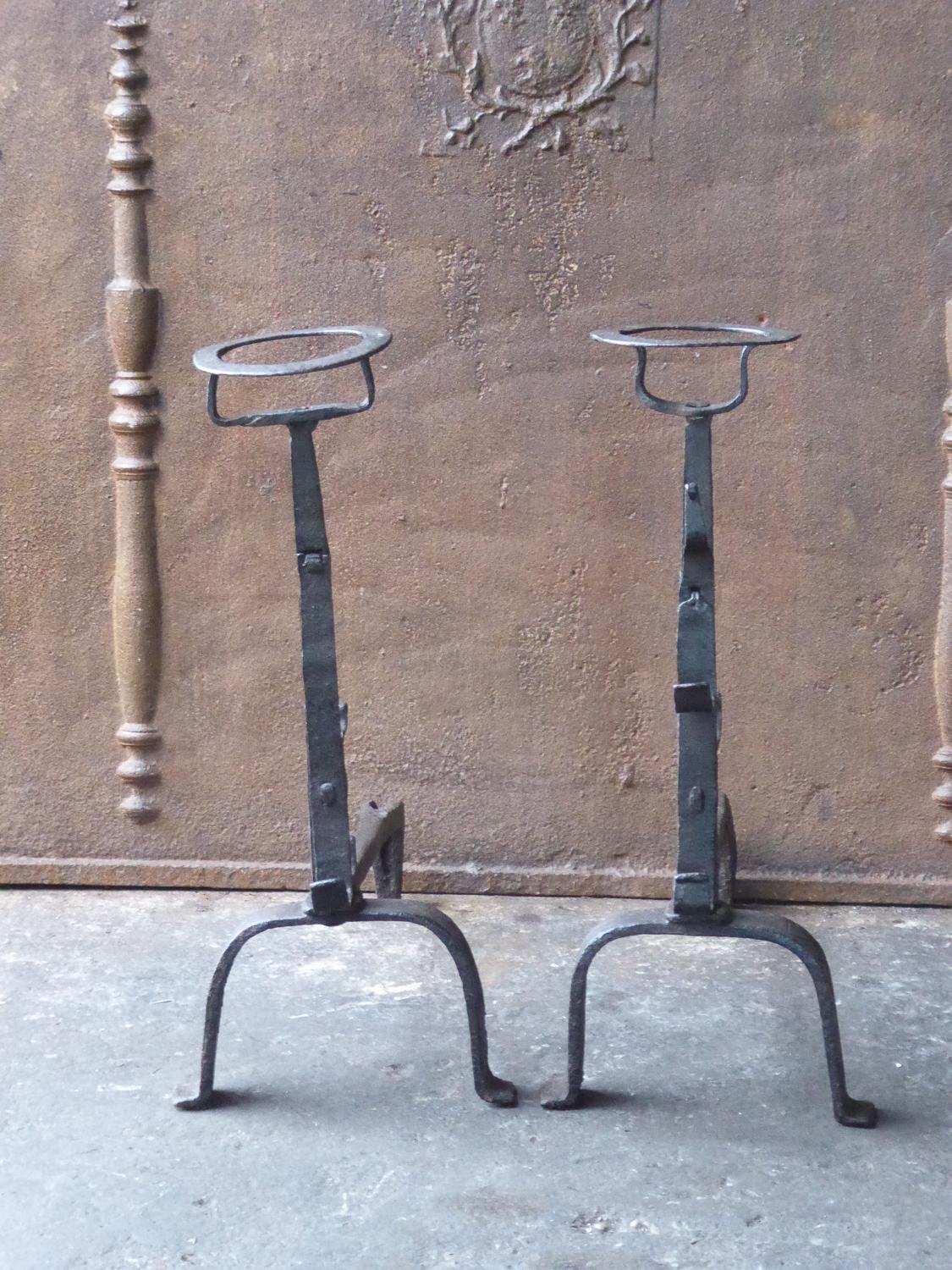 17th-18th century French andirons made of wrought iron. The style of the andirons is gothic. The andirons have spit hooks to grill food. They have a natural brown patina. The condition is good.