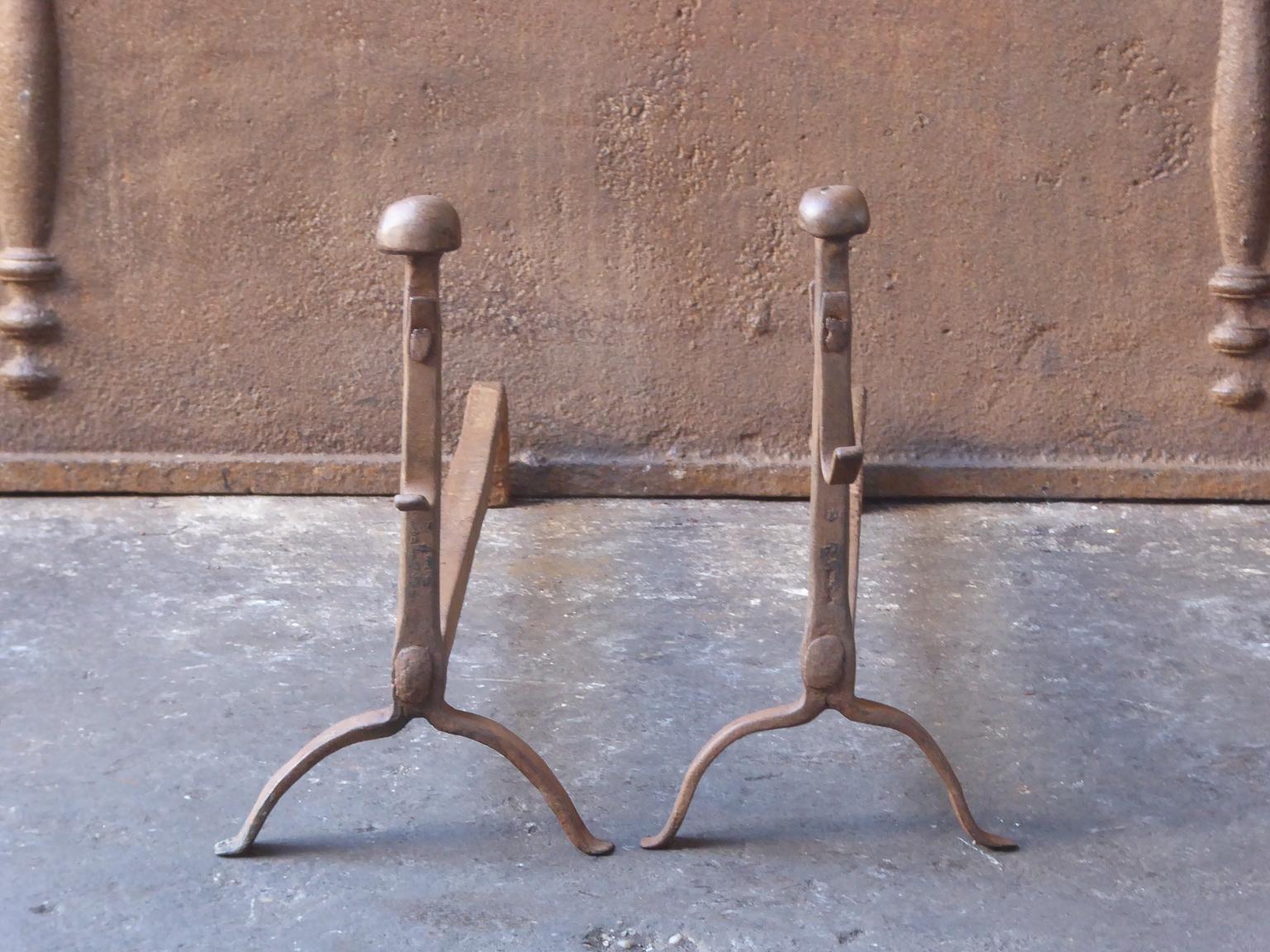 17th-18th century French andirons made of wrought iron. The style of the andirons is gothic. The andirons have spit hooks to grill food. They have a natural brown patina. Upon request it can be made black. The condition is good.