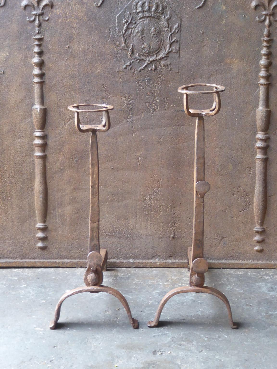 17th-18th century French andirons made of wrought iron. The style of the andirons is gothic. The andirons have spit hooks to grill food. They have a natural brown patina. Upon request it can be made black.