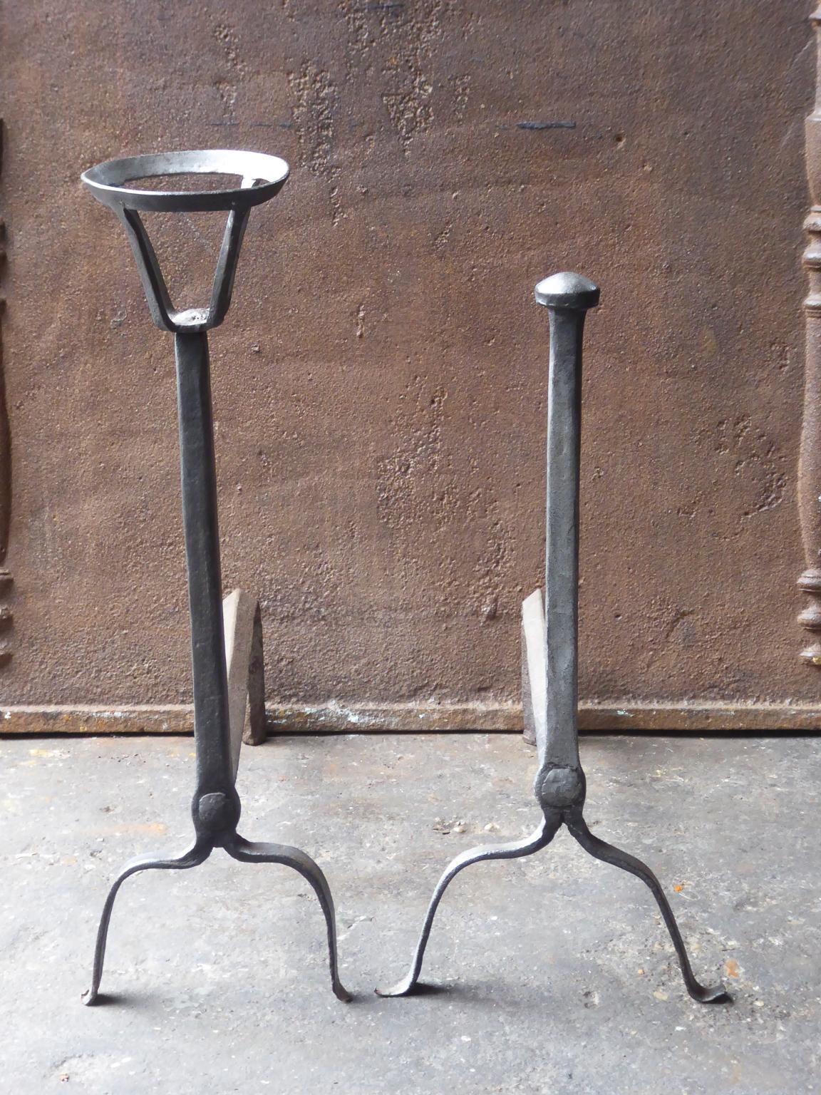 17th-18th century French andirons made of wrought iron. The style of the andirons is gothic. The andirons have spit hooks to grill food. Wedding pair whereby both parties donate one andiron from the same blacksmith. The condition is good.