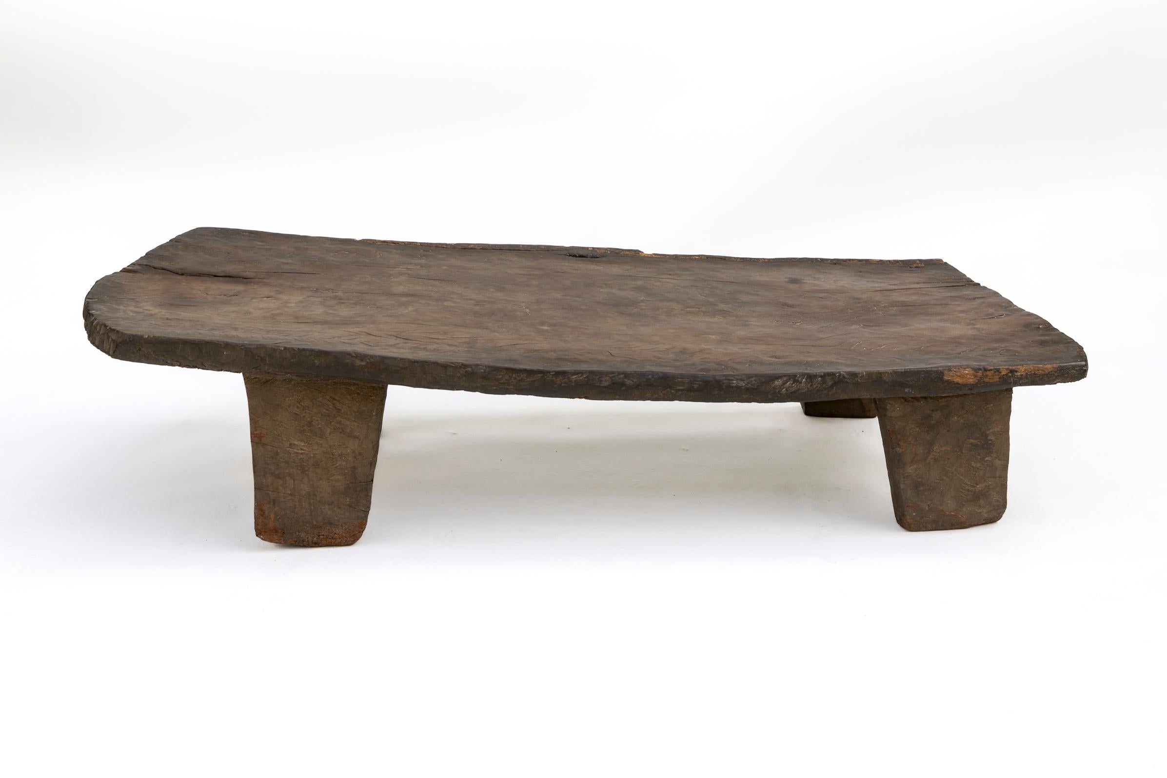 Exemple frappant de mobilier tribal ancien du Nagaland, dans le nord-est de l'Inde, ce lit bas ou plate-forme a été sculpté à la main dans un seul bloc massif de bois dur, avec des pieds et un plateau intégrés formés à partir de la même pièce.