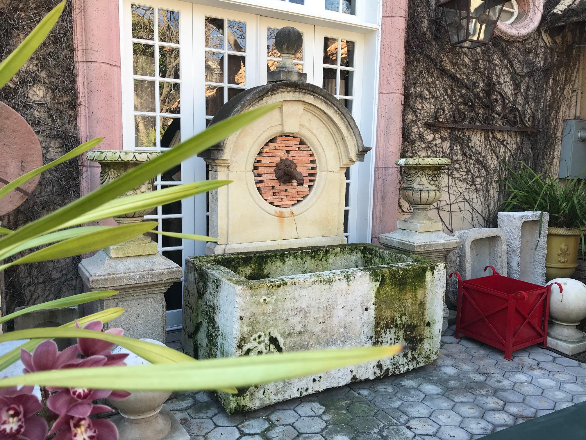 This exquisite water fountain is created of beautifully carved old elements. A rare late 17th-early 18th century stone window Oeil-de-boeuf from an old Chateau in Dordogne.
It's crowned with a handsome stone sphere finial. The mythical dolphin spout