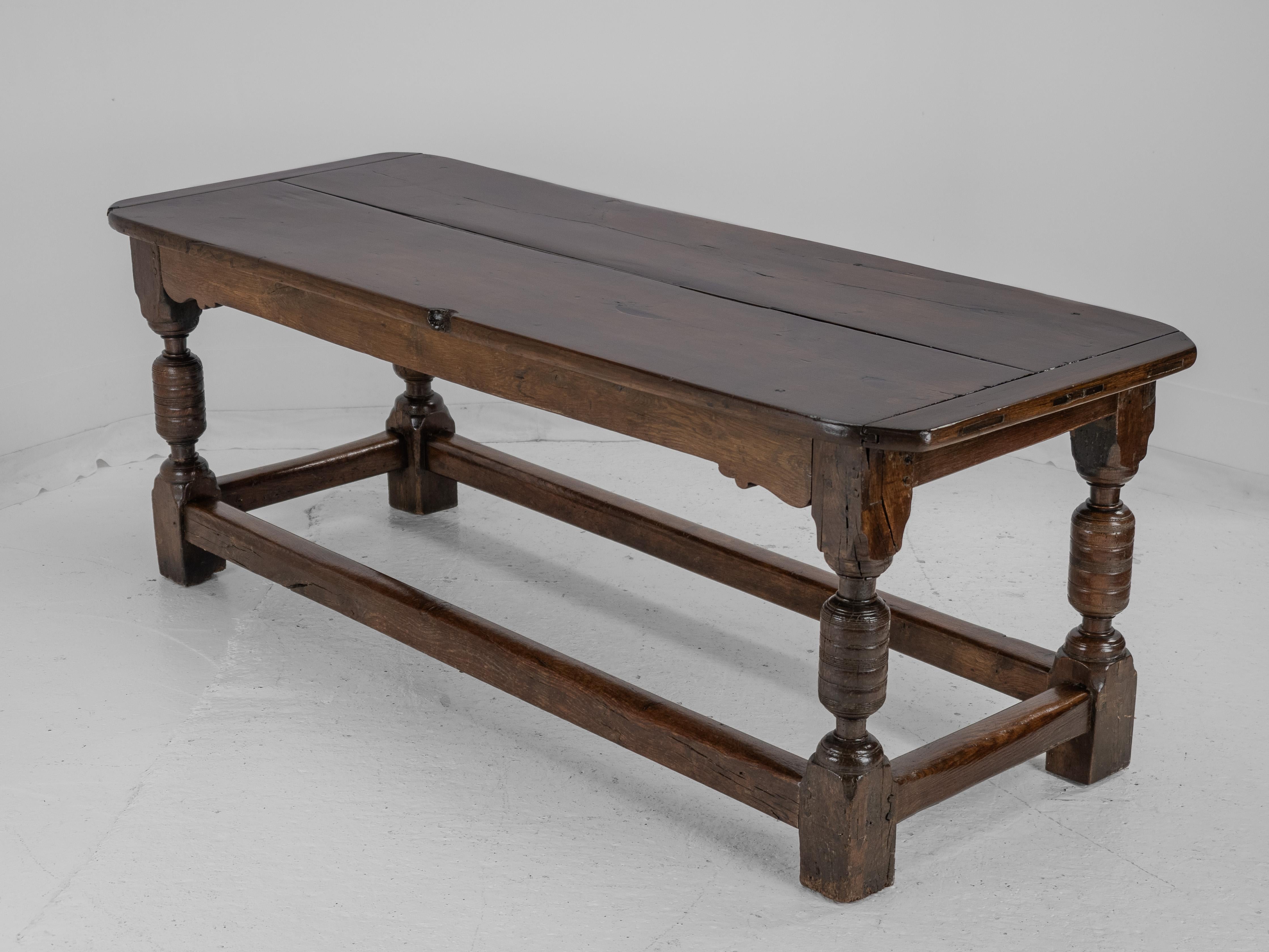 This 17th and 18th century oak refectory table has 17th century base and 18th century top. The early 18th century top is a double board plank top with cleated bread-board ends. The mid 17th century base features one side frieze with scrolled lower