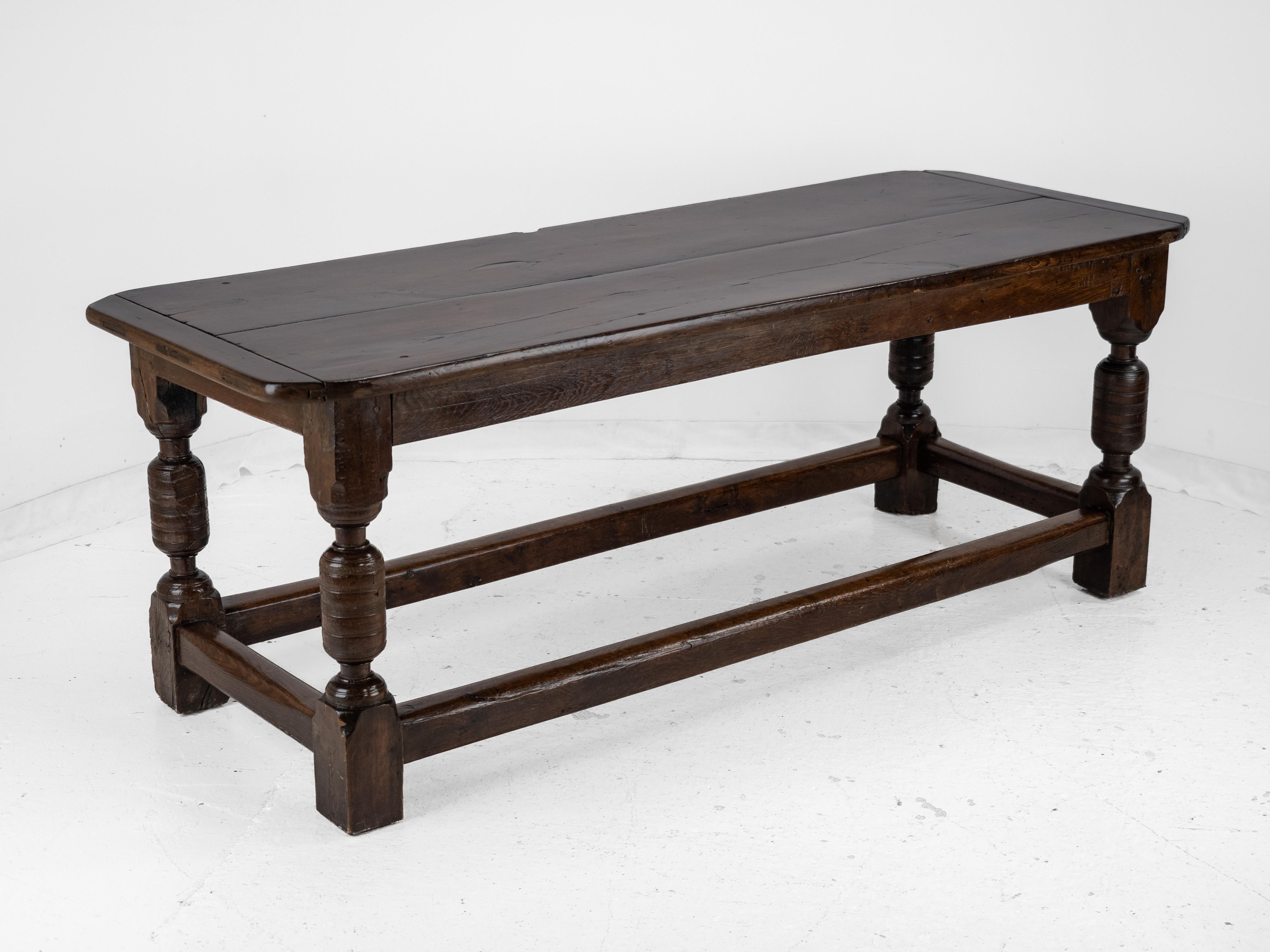 This 17th and 18th century oak refectory table has 17th century base and 18th century top. The early 18th century top is a double board plank top with cleated bread-board ends. The mid 17th century base features one side frieze with scrolled lower