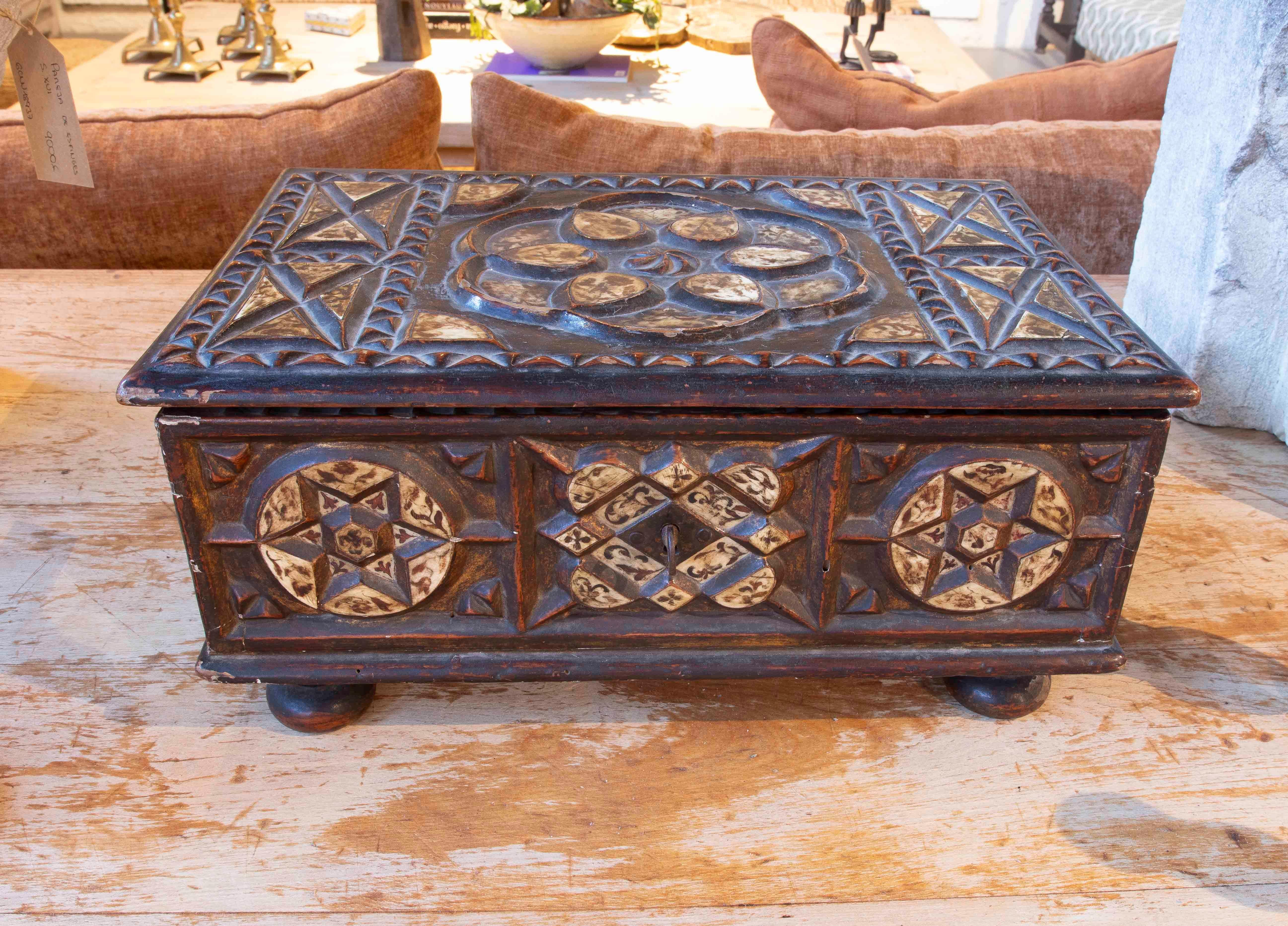 Magnificent antique hand-carved wooden chest, decorated with intricate geometric motifs and inlays in light tones that contrast with the dark background. The design features stars, diamonds, and intertwined circles that evoke the artisanal tradition