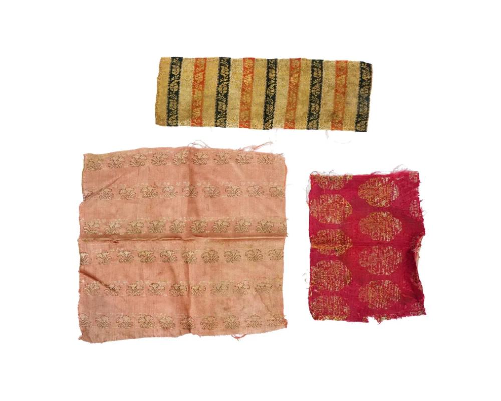 Un gruppo di tre antichi frammenti tessili ricamati a mano della dinastia iraniana Safavid, circa 17° secolo. Il primo tessuto presenta strisce verticali alternate in oro, rosso e nero con motivi floreali dettagliati. Il secondo è un tessuto rosa