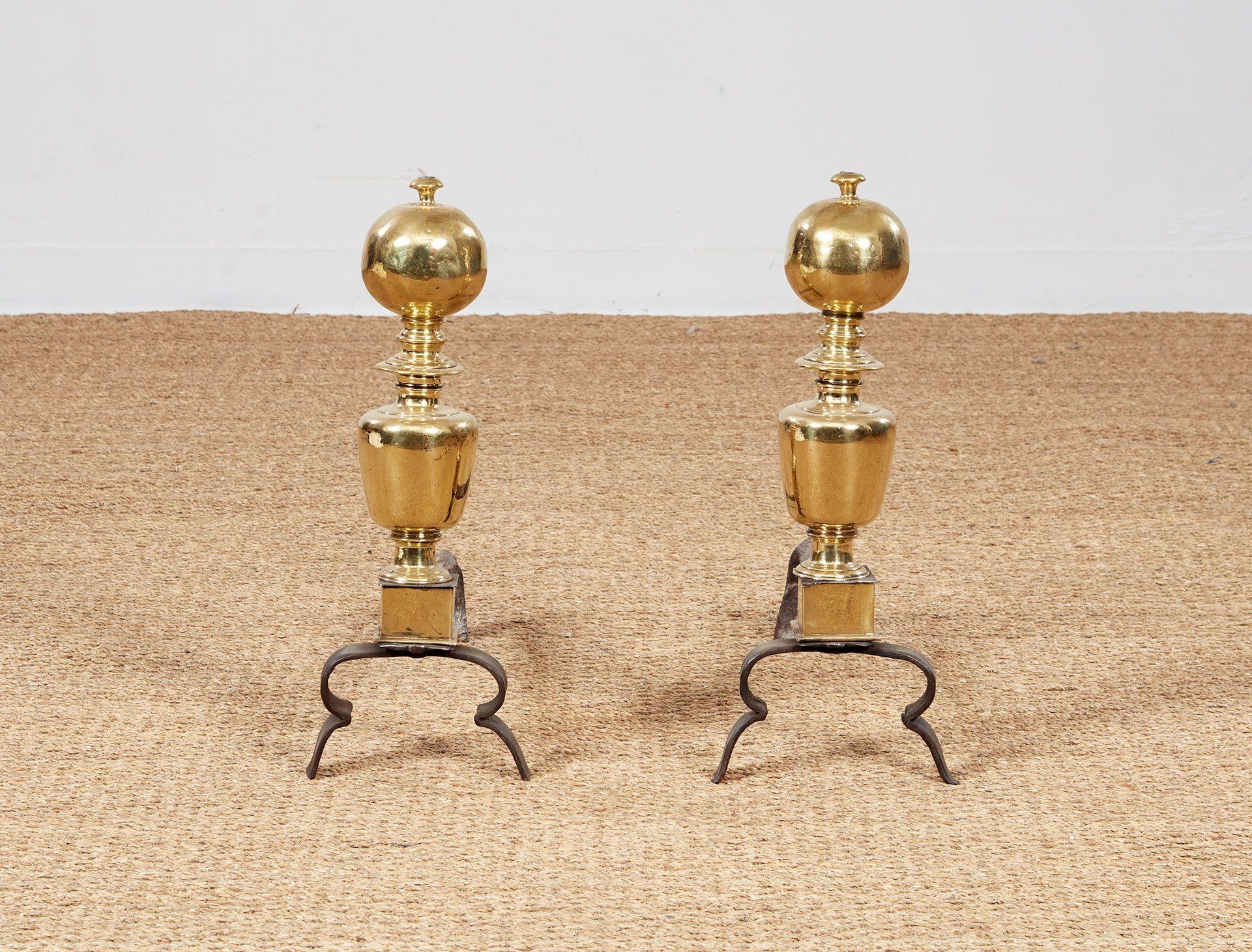 Pair of late 17th century baroque brass and iron andirons having large ball finials over ring turned necks, the bodies of balustrade form with square plinth bases, over wrought iron legs with double hoops.