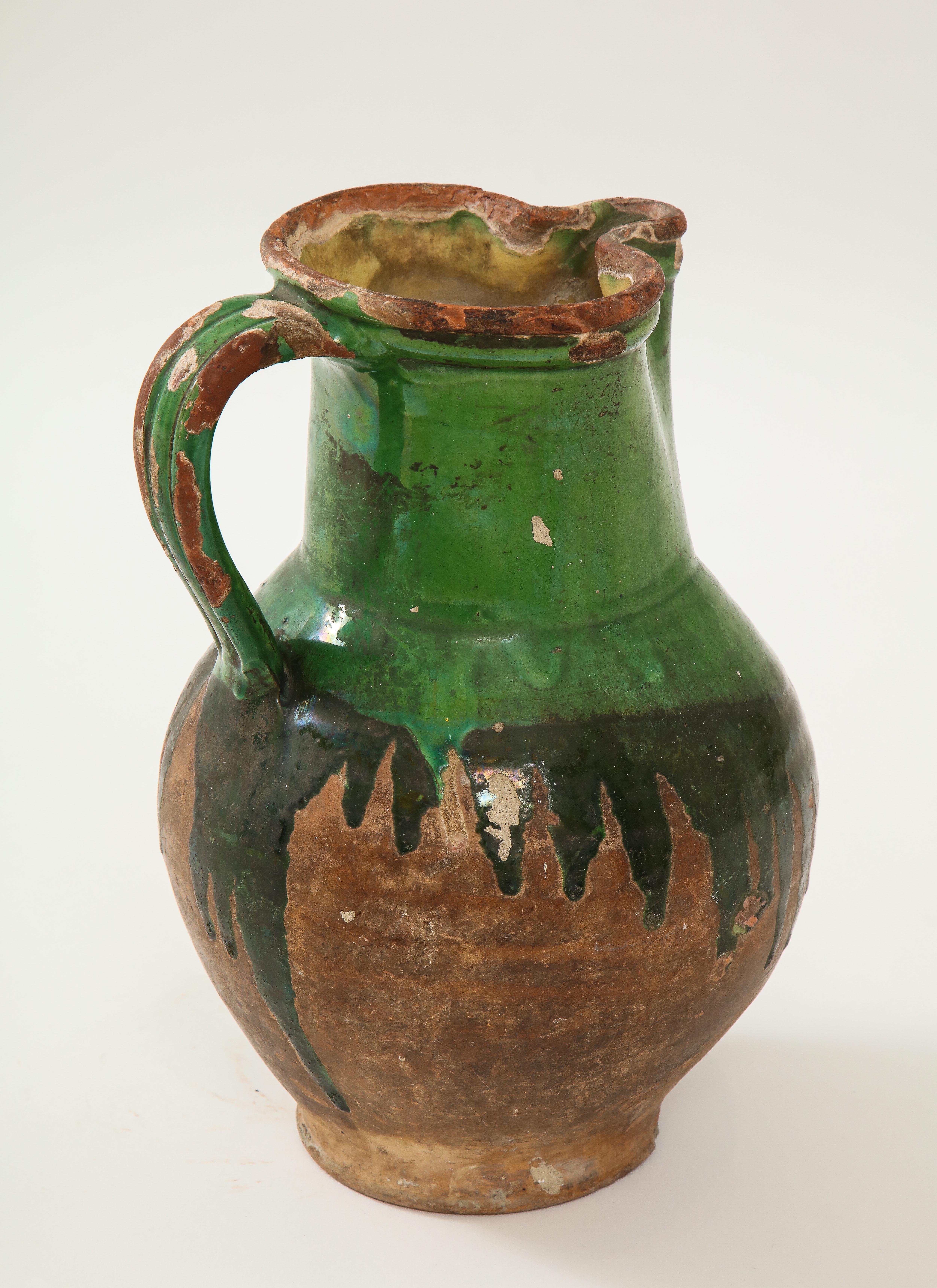 This is a very rare large pitcher from Friesland from the 17th century. The yellow interior glaze with the careless outer green glaze is typical of this period and is traditional Fresian. The Dutch were making this type of earthenware as early as