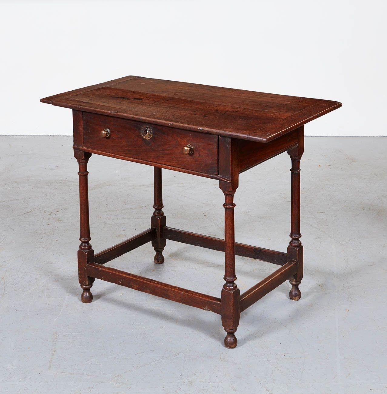 A very good oak side table having overhanging two-plank top with wide cleated ends over single drawer with central escutcheon and a pair of turned wood knobs over tapered and ring-turned legs on knob feet joined by molded box stretcher. Nice