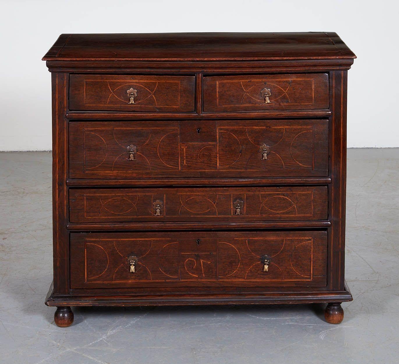 A 17th century oak chest of drawers dated 1679, having wonderful string inlaid lines and bands, with two short top drawers over three long drawers, each drawer separated by concave molding, having brass drop pulls. Inlaid side stiles and architrave