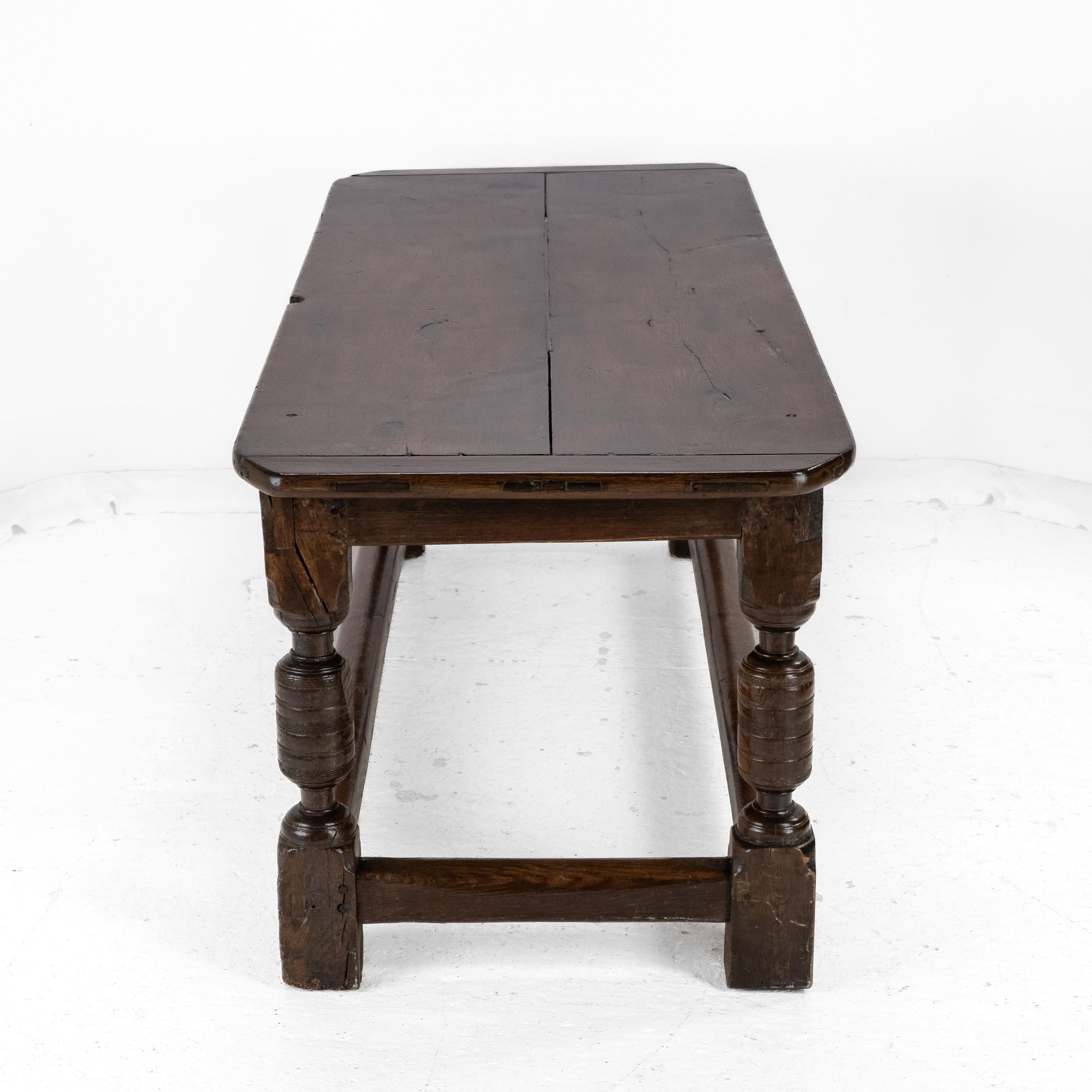 This 17th and 18th century oak refectory table has 17th century base and 18th century top. The early 18th century top is a double board plank top with cleated bread-board ends. The mid 17th century base features one side frieze with scrolled lower
