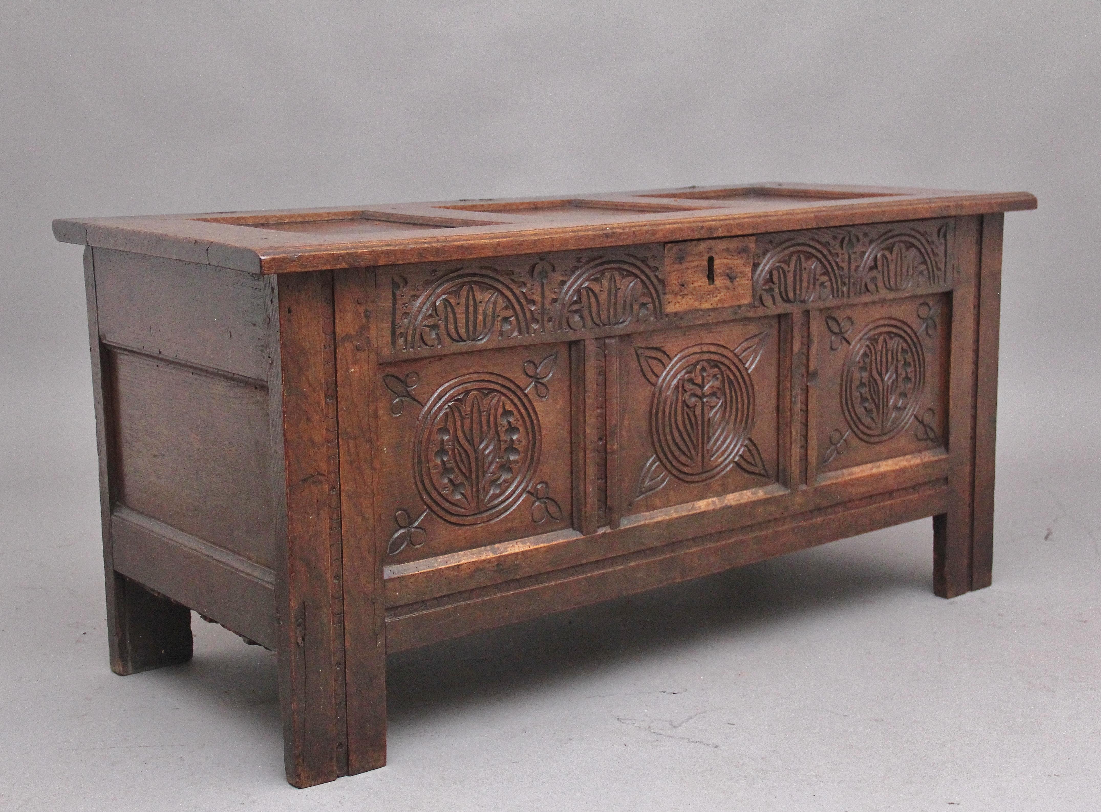 17th century oak coffer with the hinged three panelled top above a three panelled front with carved decoration, a wonderfully carved top rail above the three panelled front, standing on square legs. Circa 1680.
  