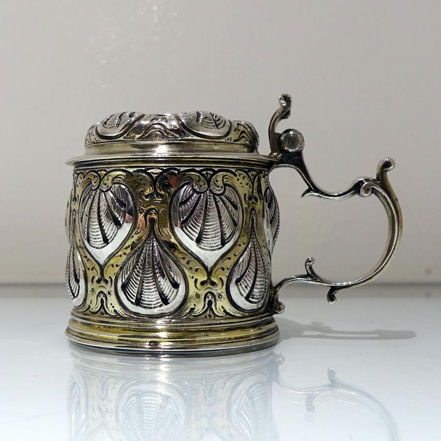 A truly stunning 17th century partial gilt “ladies” tankard and cover beautifully decorated with hand embossed shells. The lid is hinged and the elegantly designed wirework handle and thumbpiece create a truly impressive work of craftsmanship.

