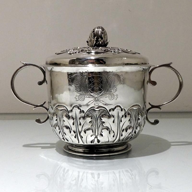 A stunning James II silver porringer and cover decorated with elegant acanthus leaf designs to the lower bowl. The centre front and back have elegant contemporary armorial/initials for importance. The ornate lid is detachable and crowned with a