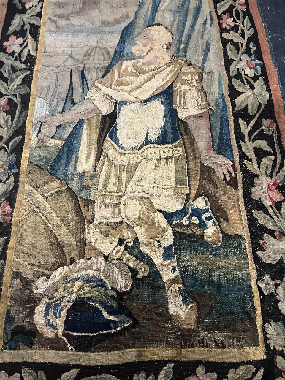 Un fragment de tapisserie d'Aubusson du XVIIe siècle représente un homme à genoux regardant vers le haut, visité par un ange rayonnant. Des couleurs riches et des détails complexes capturent l'instant de la rencontre divine. La délicatesse de