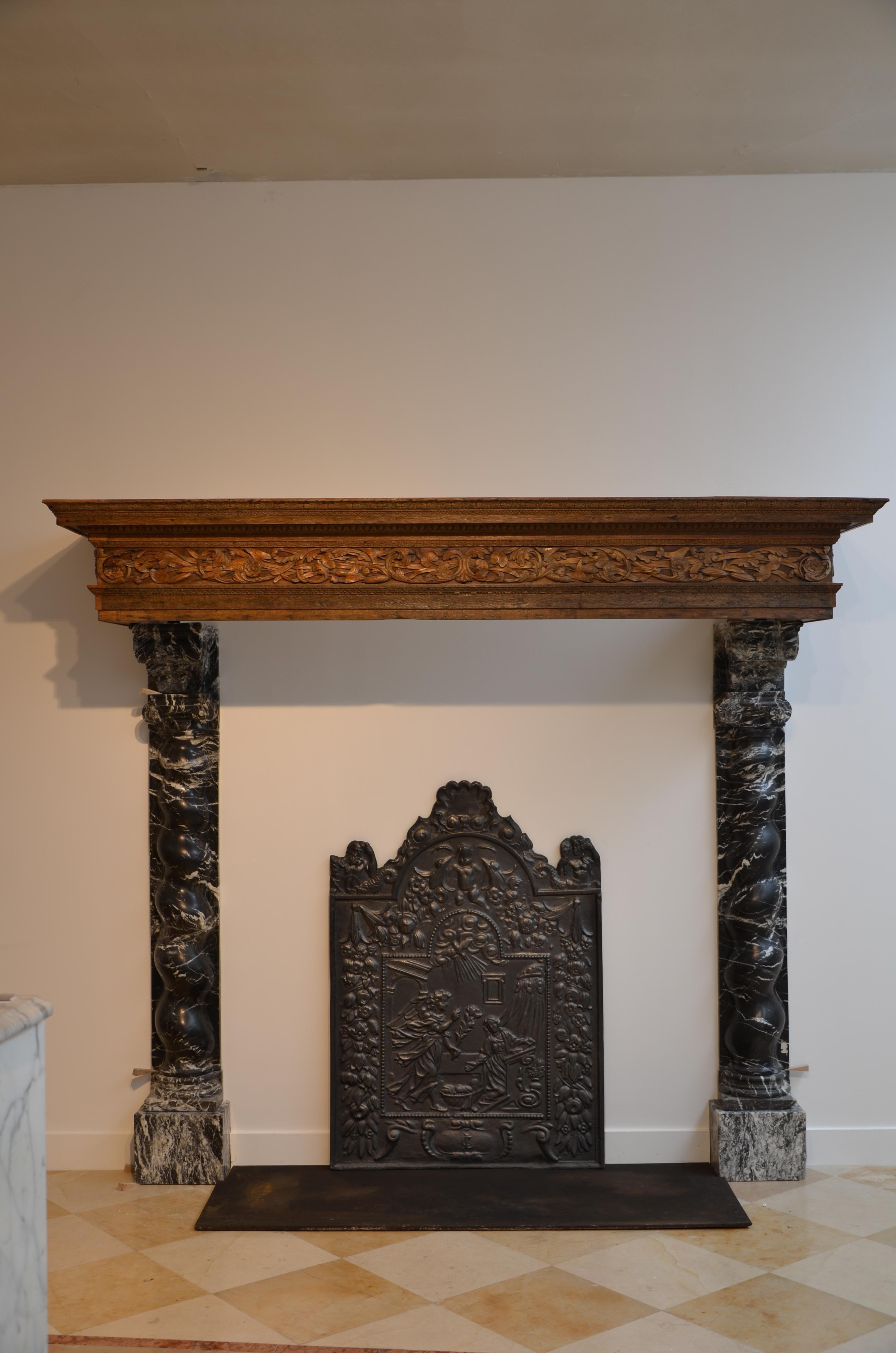 Large and amazing Baroque Dutch mantelpiece from the 17th century.
Very well decorated limewood frieze displays an array of beautiful water plants, supported by black and white veined marble jambs. Cast iron floor and fireback finish this mantel