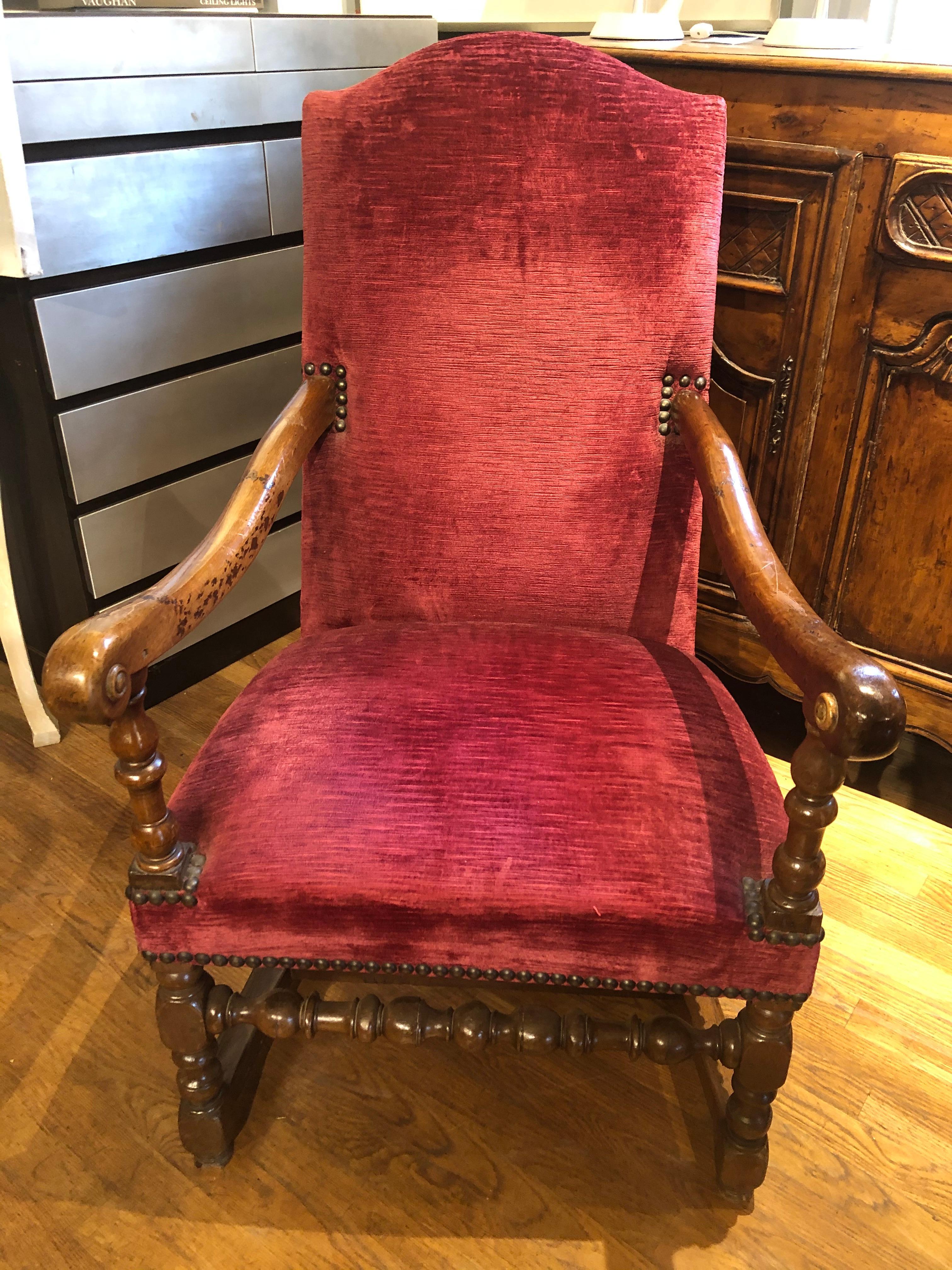 Beautiful 17th century Baroque French Provincial armchair upholstered in a rich raspberry red velvet. Arched back, sweeping arms and turned legs with stretchers. This lovely armchair is made of a deeply patinated walnut with lustrous color.