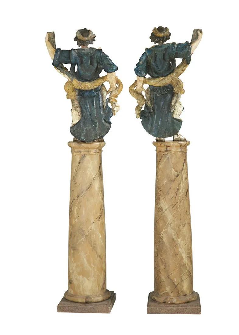 17th Century (Baroque) pair of Italian carved and polychromed figures. Each statue is holding a torchere and are mounted on their original turned wooden faux marble column.
 