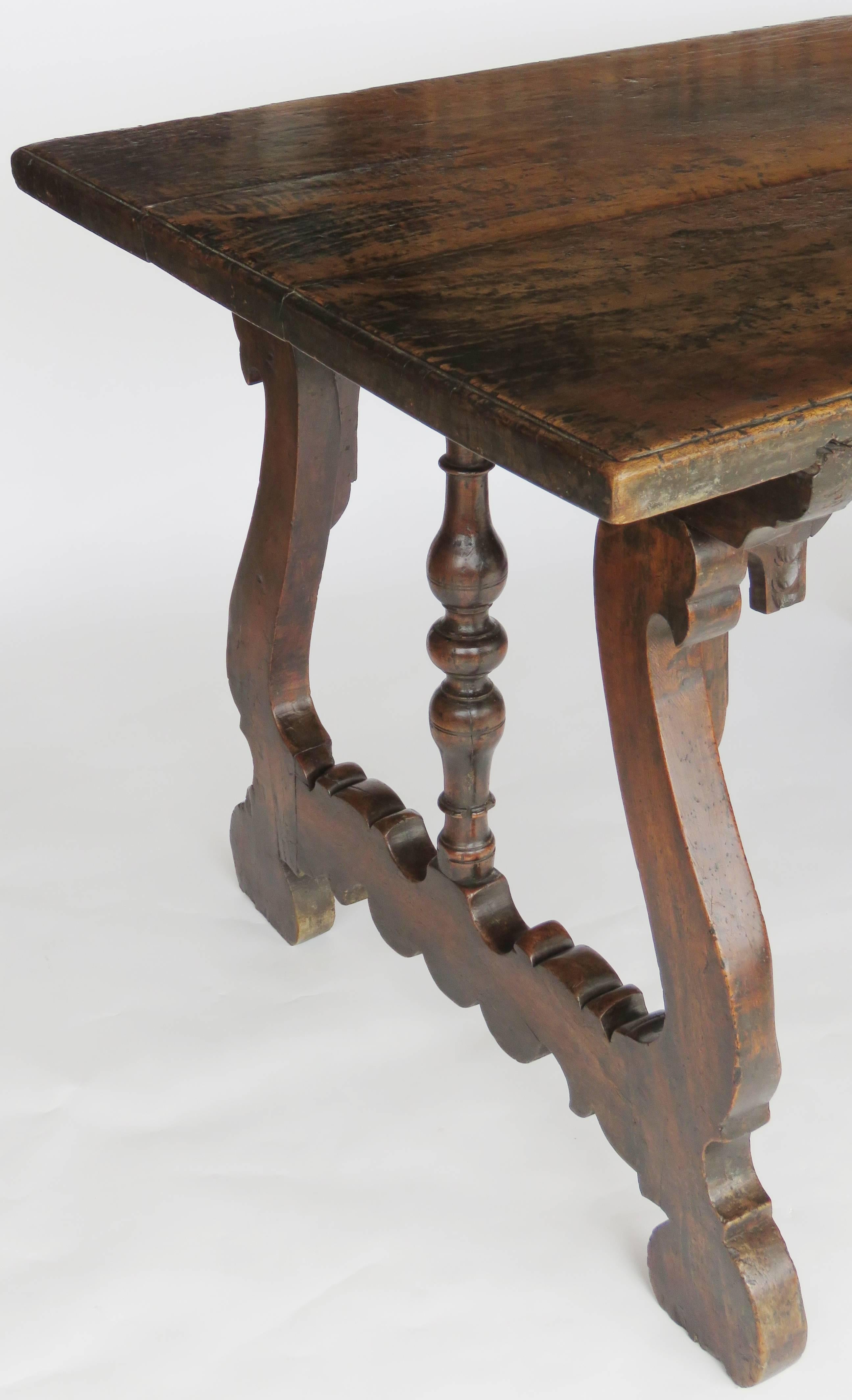 Rectangular two plank moulded top raised on shaped scrolling trestle legs united by similar stretcher with ring and baluster turned column, secured by scrolling supports.