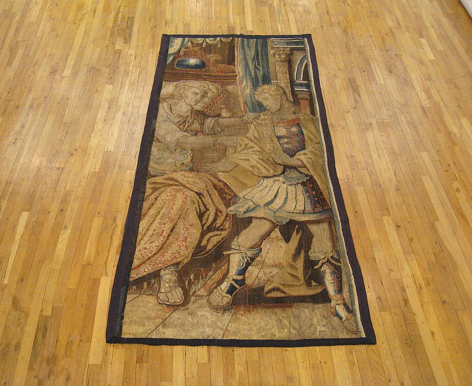 A Brussels Old Testament biblical tapestry from the 17th century, depicting Potiphar’s wife, Zoleikha attempting to seduce Joseph. The two figures appear in a dimensional interior setting, and the scene is enclosed within a narrow monochromatic
