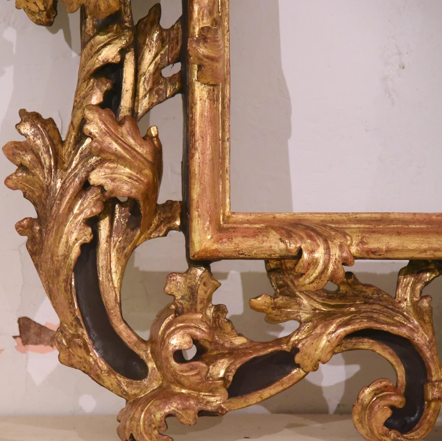 Refined Brustolon frame, mirror from the 1600s Venetian school, in richly carved wood with large curved leaves, typical of the Brustolon style, the gilding is in gold leaf.
