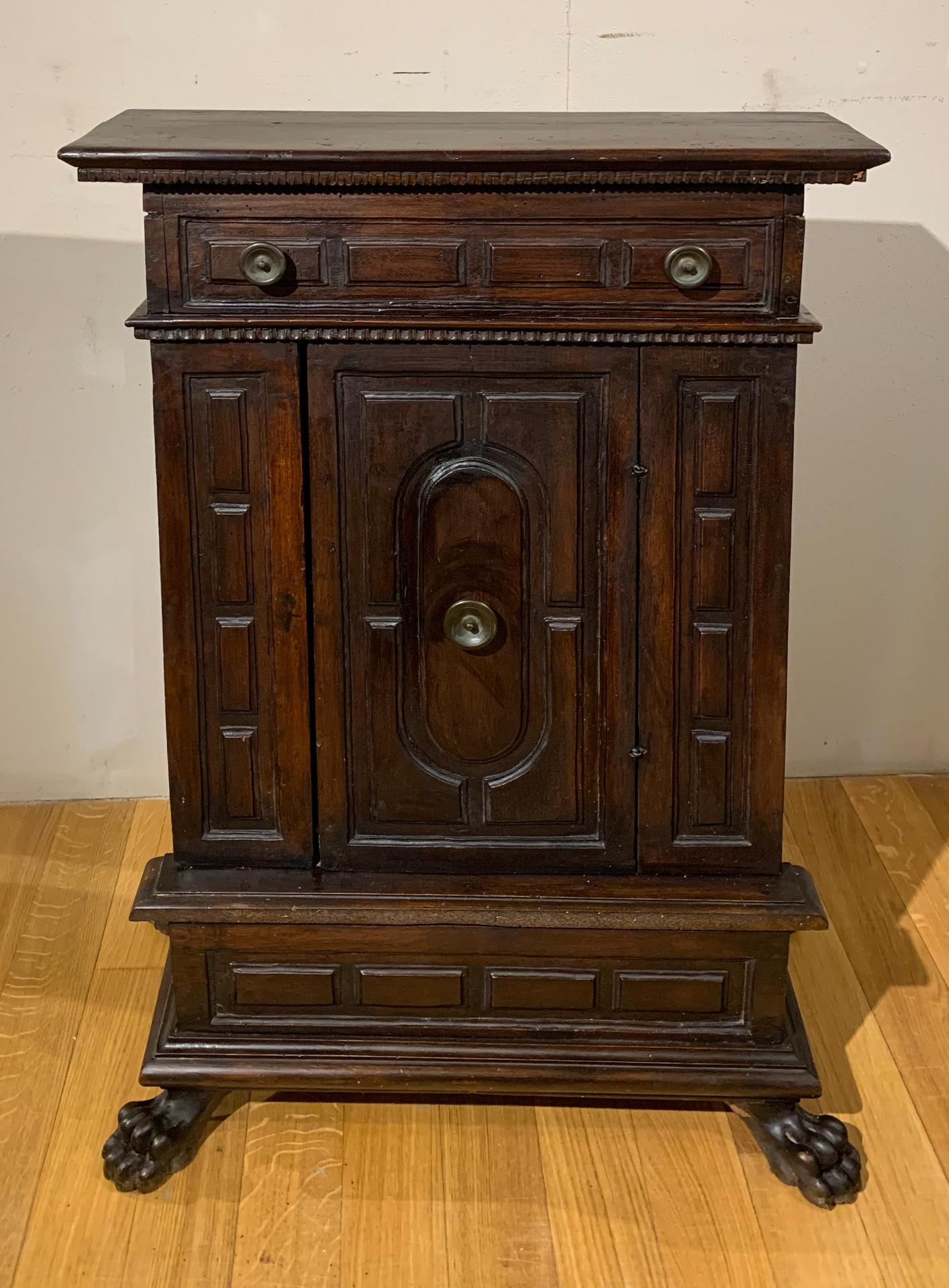 Nice sideboard in solid walnut with ashlar paneling with geometric patterns and dark patina. It has a door in the central part with a small drawer under the top. The base is refined with 4 finely carved feral legs. The particularity of the piece of