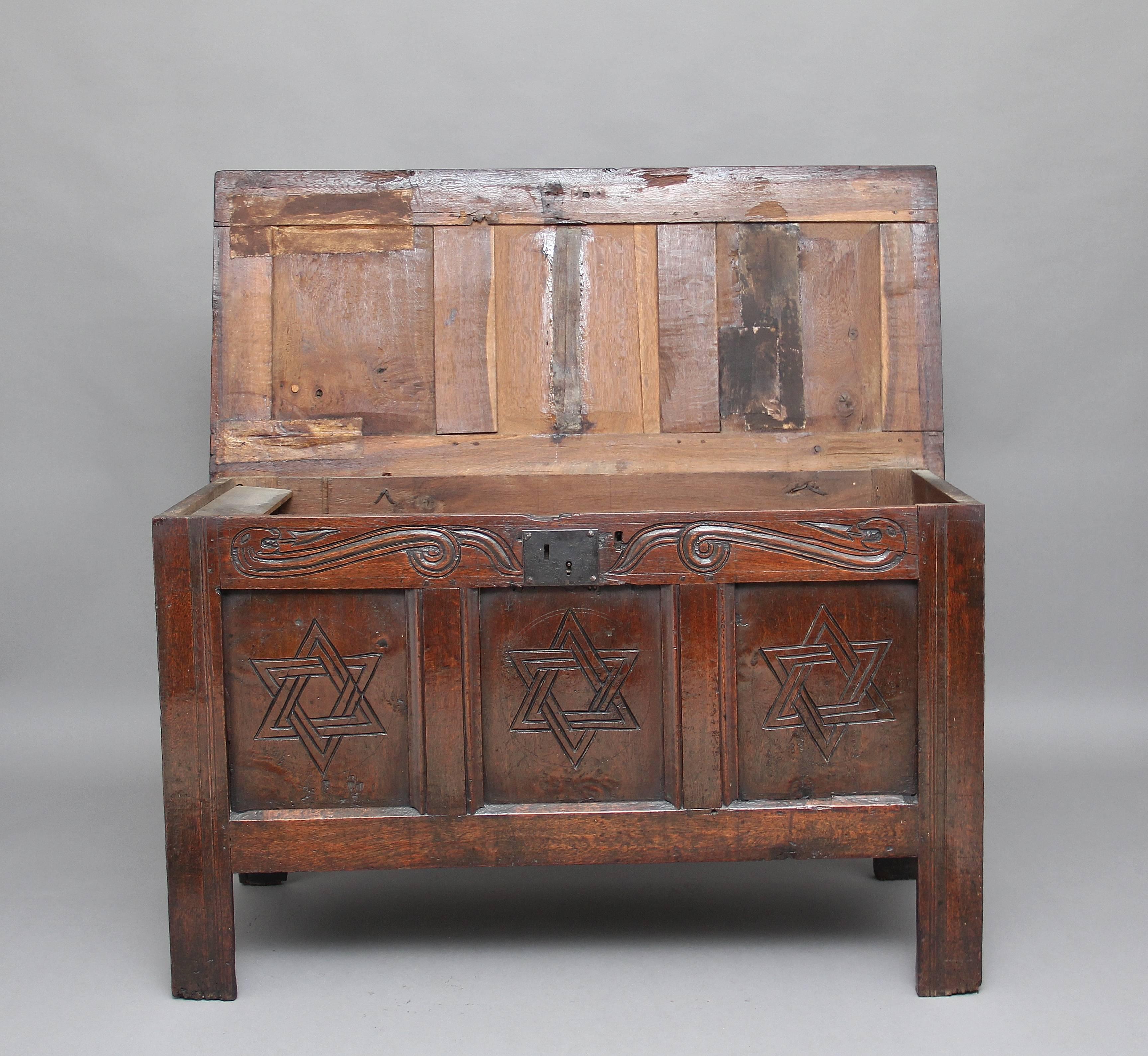 17th century oak coffer with the hinged three panelled top above a three panelled front with carved decoration, a wonderfully carved top rail above the three panelled front, standing on square legs, circa 1680.
     
