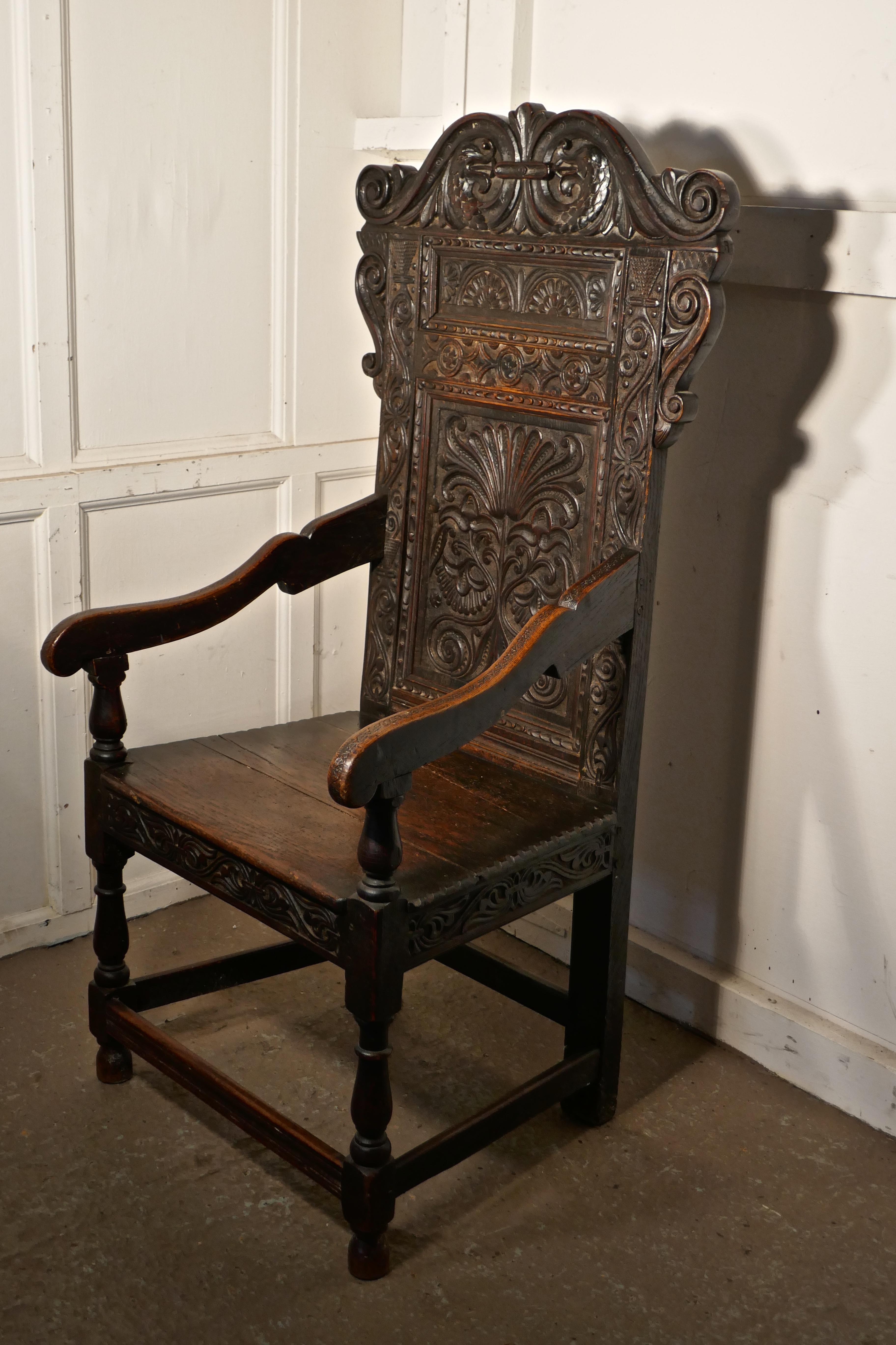 17th century carved oak wainscot chair

This Handsome Chair, has a magnificent patina, the solid plank seat has a carved border at the front, the turned legs and uprights support the arm rests, all set off with a decorative high carved throne back