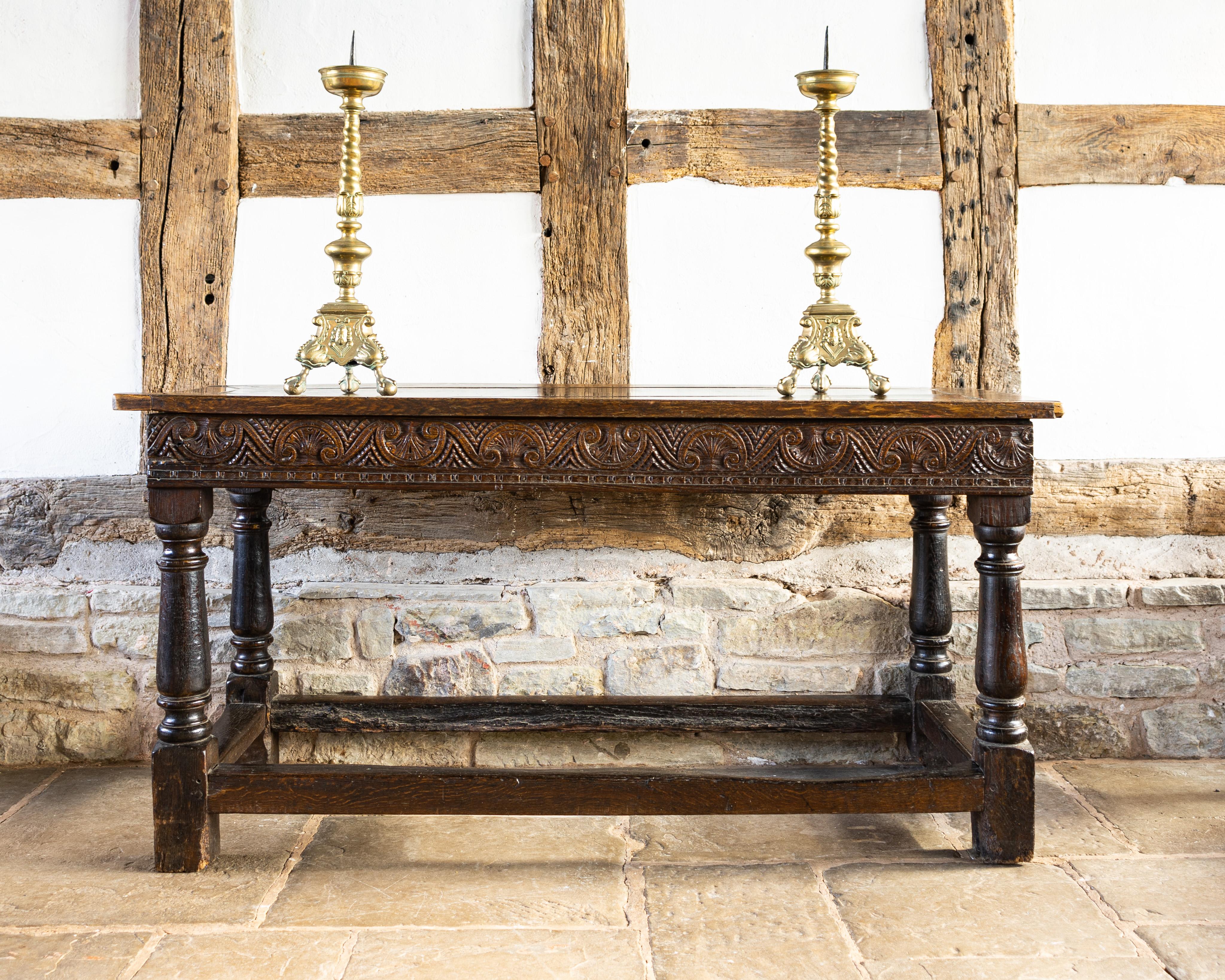 Charles I carved oak table having a planked top, the front and side rails carved with alternating leaf guilloche, on baluster ring turned legs, united by thick plain stretchers.