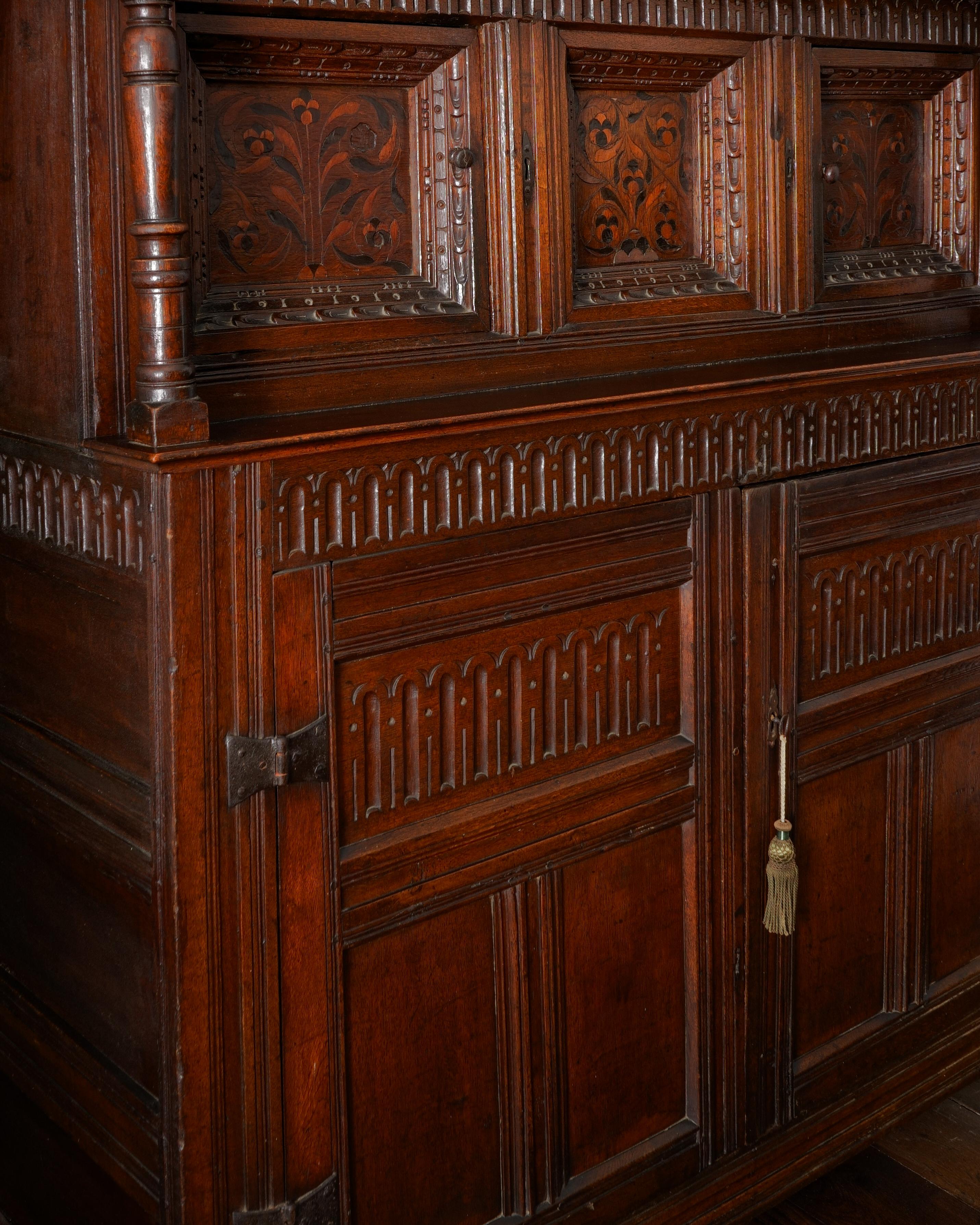 CHARLES I, OAK & INLAID COURT CUPBOARD
Yorkshire, England, Circa 1630

The frieze gauge carved to three sides, raised on baluster and reel-turned end-columns, enclosing two recessed panelled cupboard doors, each door having a floral marquetry-inlaid