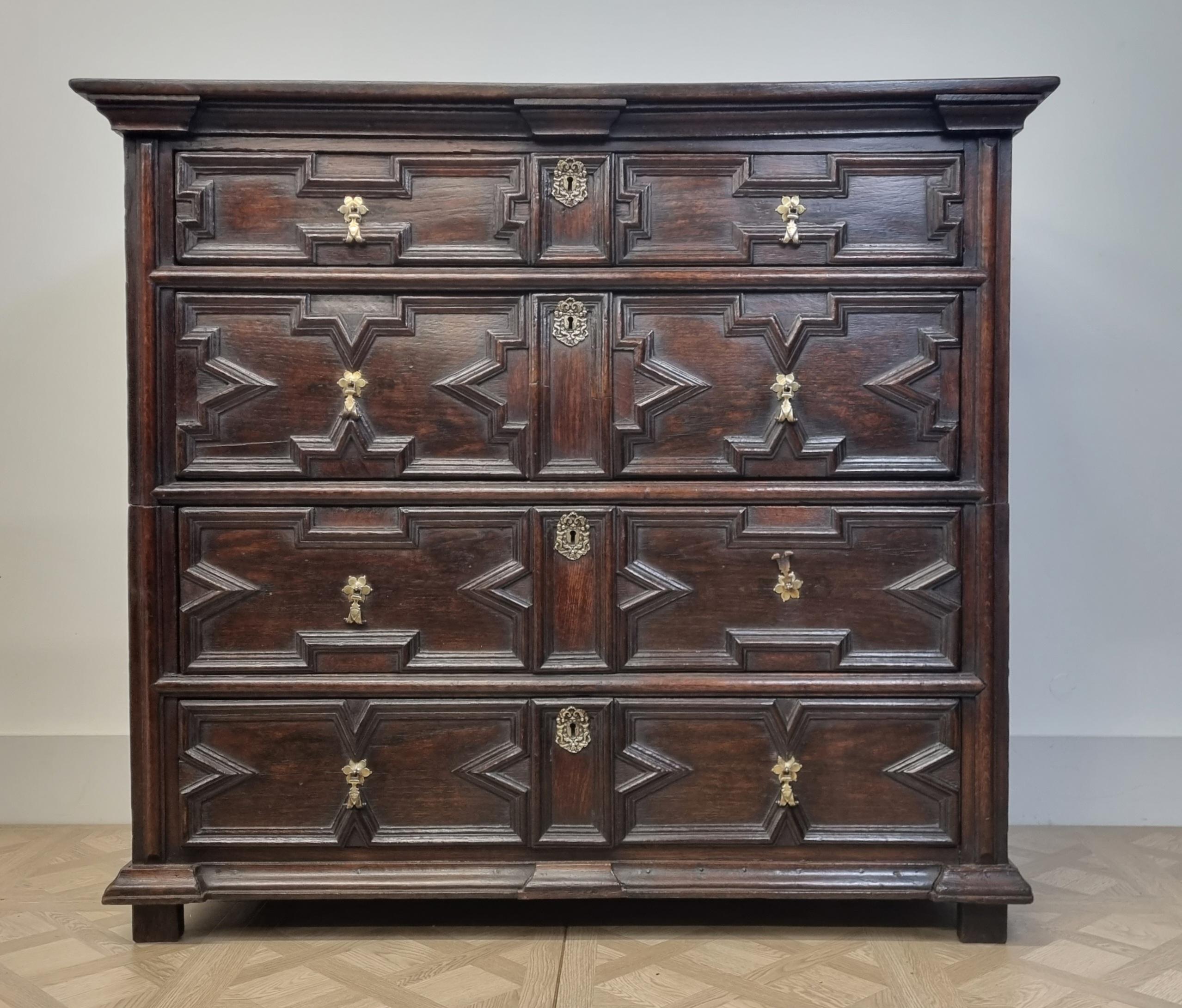 A superb 17th-century Charles II geometric chest of drawers. It features a rectangular planked top . The chest has four long drawers, lined with oak , brass drop handles, escutcheons. It stands on its original stile feet . Outstanding rich warm