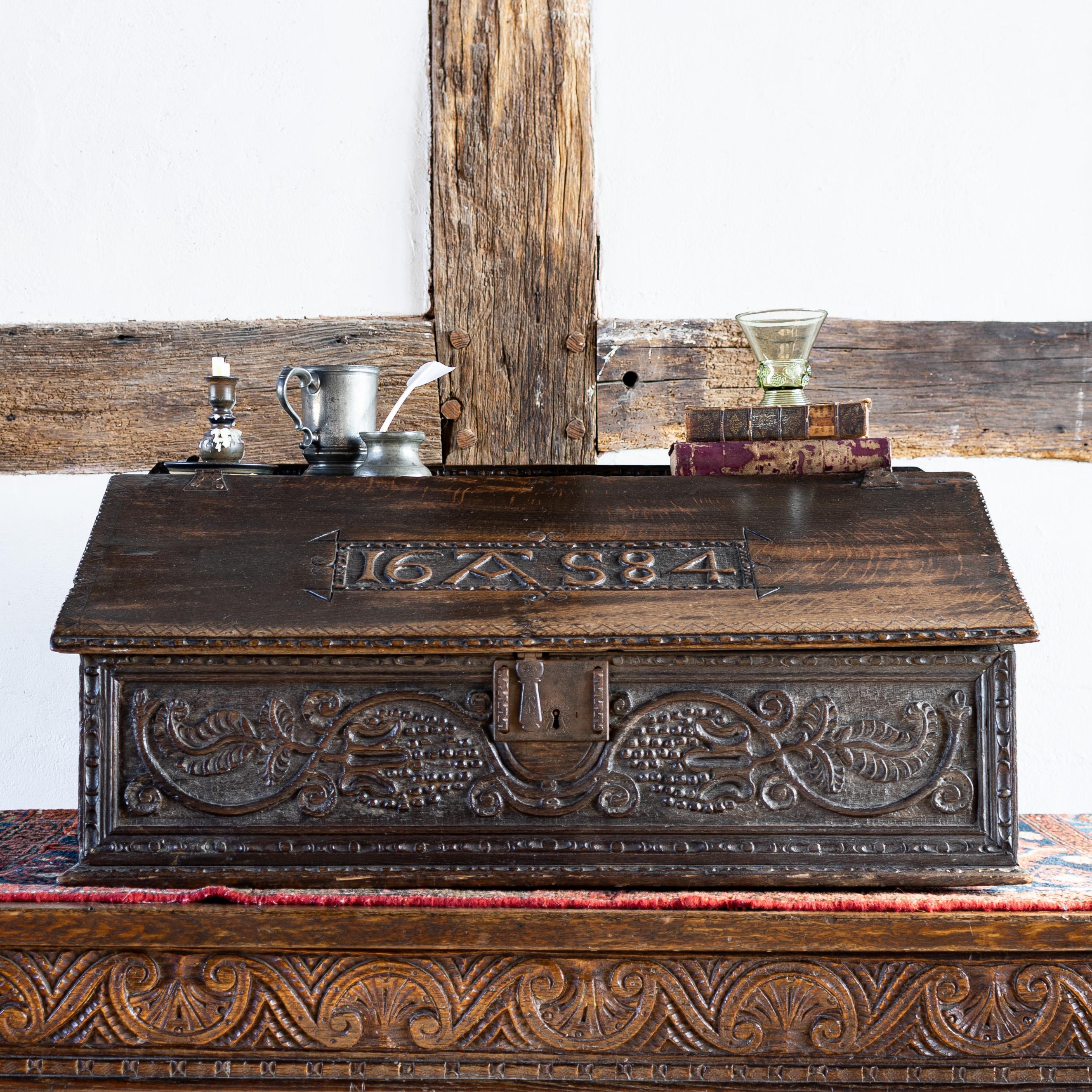 Charles II carved oak desk box of large proportions, the front carved with trailing vine & grape decoration, the lid carved with date and initials 16 AS 84, revealing three carved internal draws.