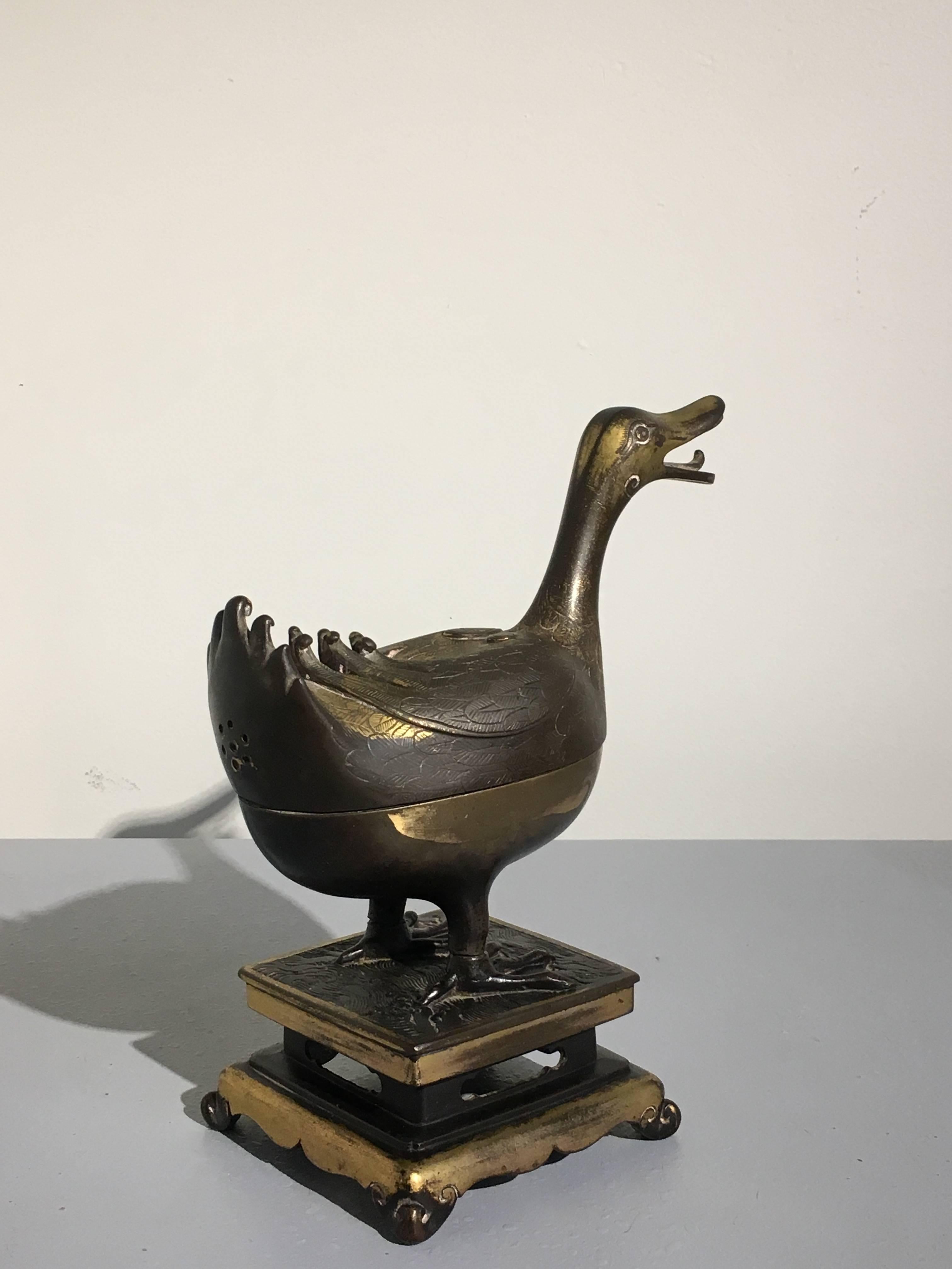 Un bel et rare encensoir chinois en bronze doré en forme de canard:: fin de la dynastie Ming:: XVIIe siècle. 

Le noble canard est représenté en position debout sur un support en bronze doré:: moulé séparément:: en forme d'incruste à taille haute