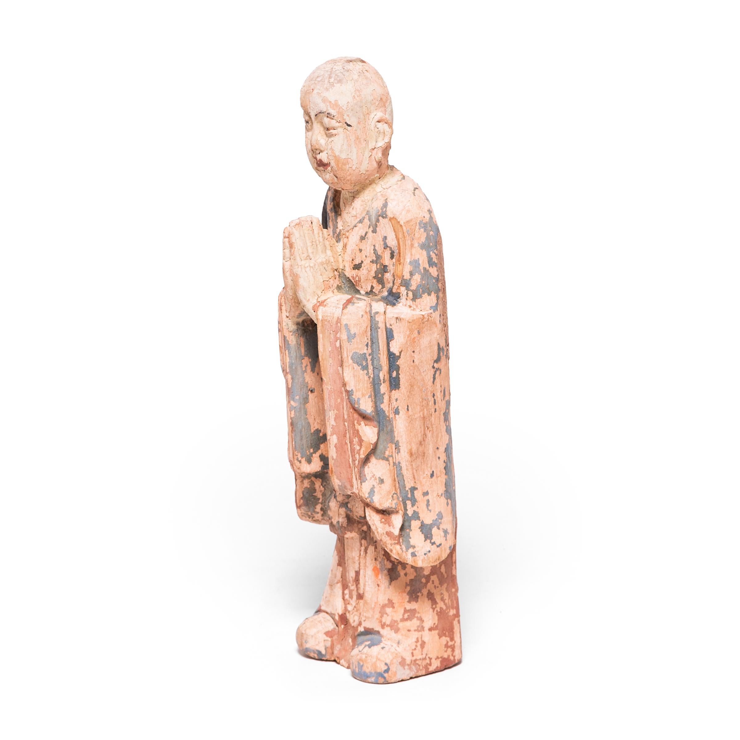 The artisan who carved and painted this unique statue managed to portray him with a sense of peace and serenity. This polychrome figure depicts a standing Buddhist monk with hands clasped in prayer. He was hand carved over 400 years ago during the