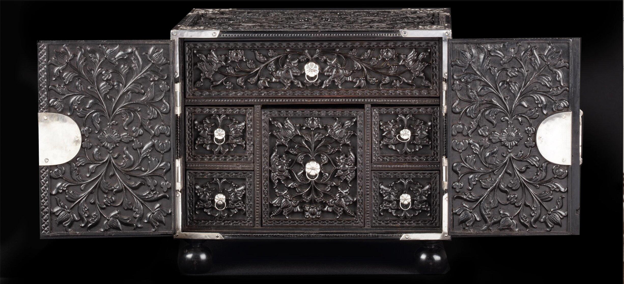 A splendid Dutch-colonial Sinhalese ebony two-door cabinet with silver mounts

Sri Lanka, Kandy, 2nd half 17th century, the mounts later

The cabinet with a central drawer with hidden compartment and the top drawer divided into four compartments.