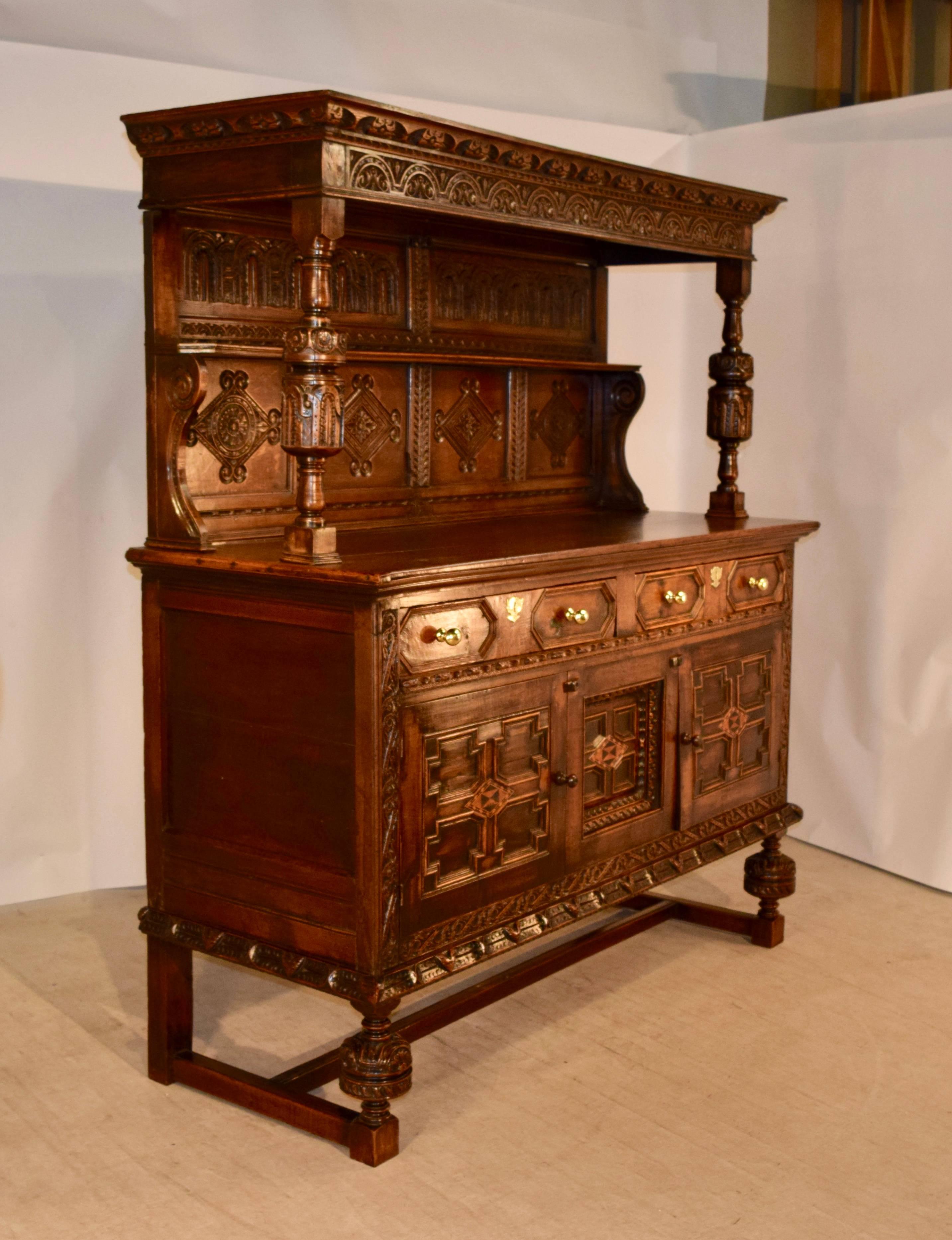 17th century oak court cupboard from England. The crown and top molding is highly decorated with exquisite hand-carving, and are supported upon hand turned and carved decorated columns, which terminate on the serving surface of the cupboard. The