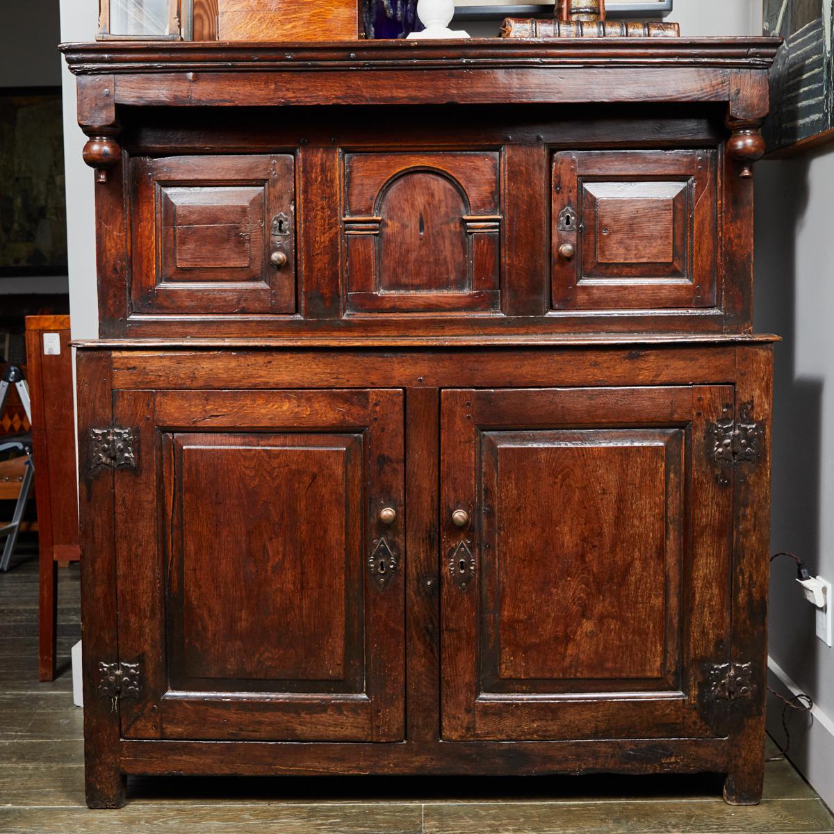 17th-century multi-paneled court cupboard from the Charles II period in England. The piece is constructed of dark oak and has a soft worn patina, giving the piece its air of emotional regality. 

England, circa 1680

Dimensions: 51W x 20D x 54.5H