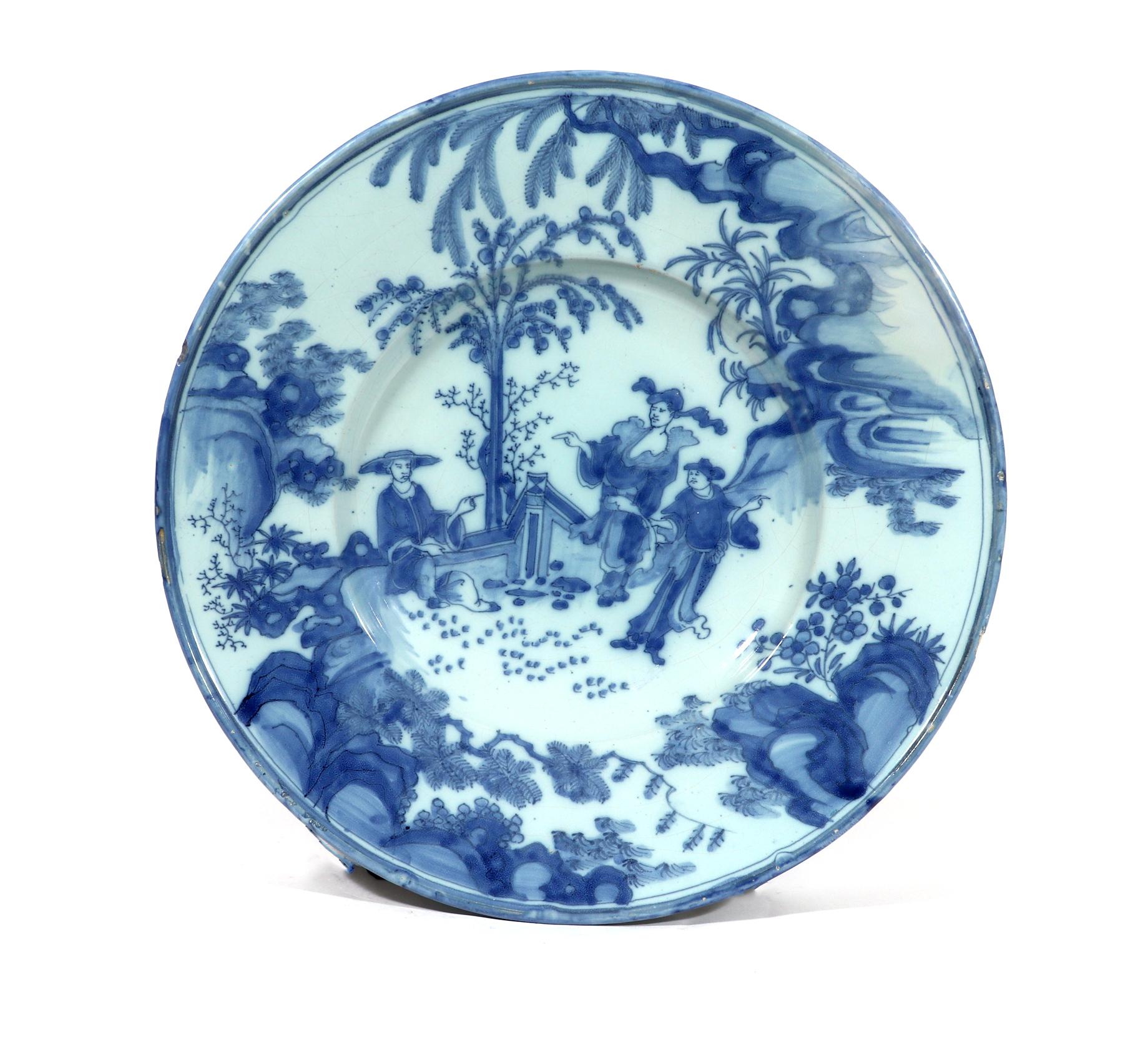 Dutch Delft large underglaze blue chinoiserie dish,
circa 1660-1680.

The large circular Dutch Delft chinoiserie dish, after the Chinese transition period blue & white, is painted with large Chinese figures in the central well surrounded by a