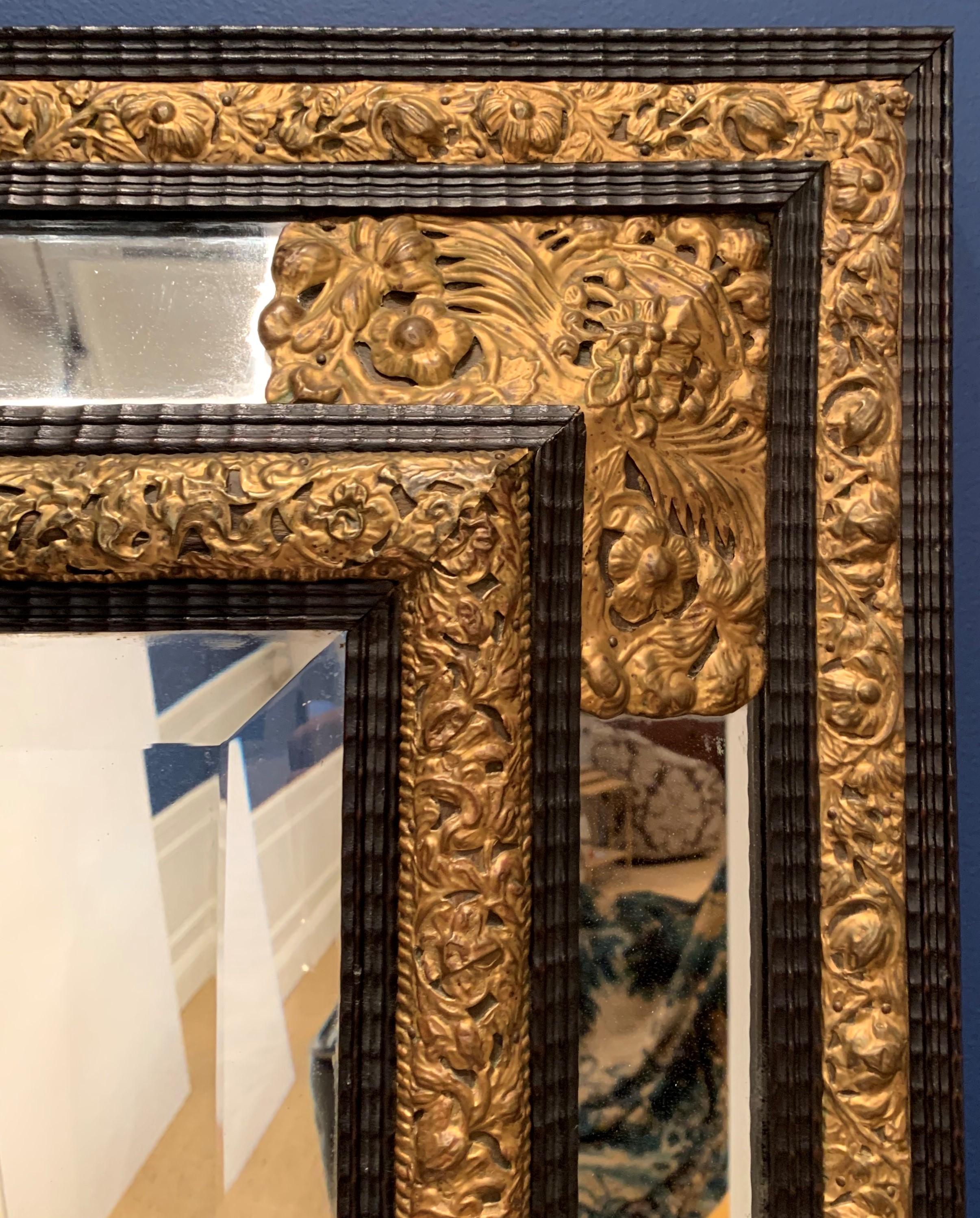 This 17th century Baroque mirror is a high example of Dutch craftsmanship. The mirror is beveled, the wood is ebonized, and the gold foliage is made of brass 