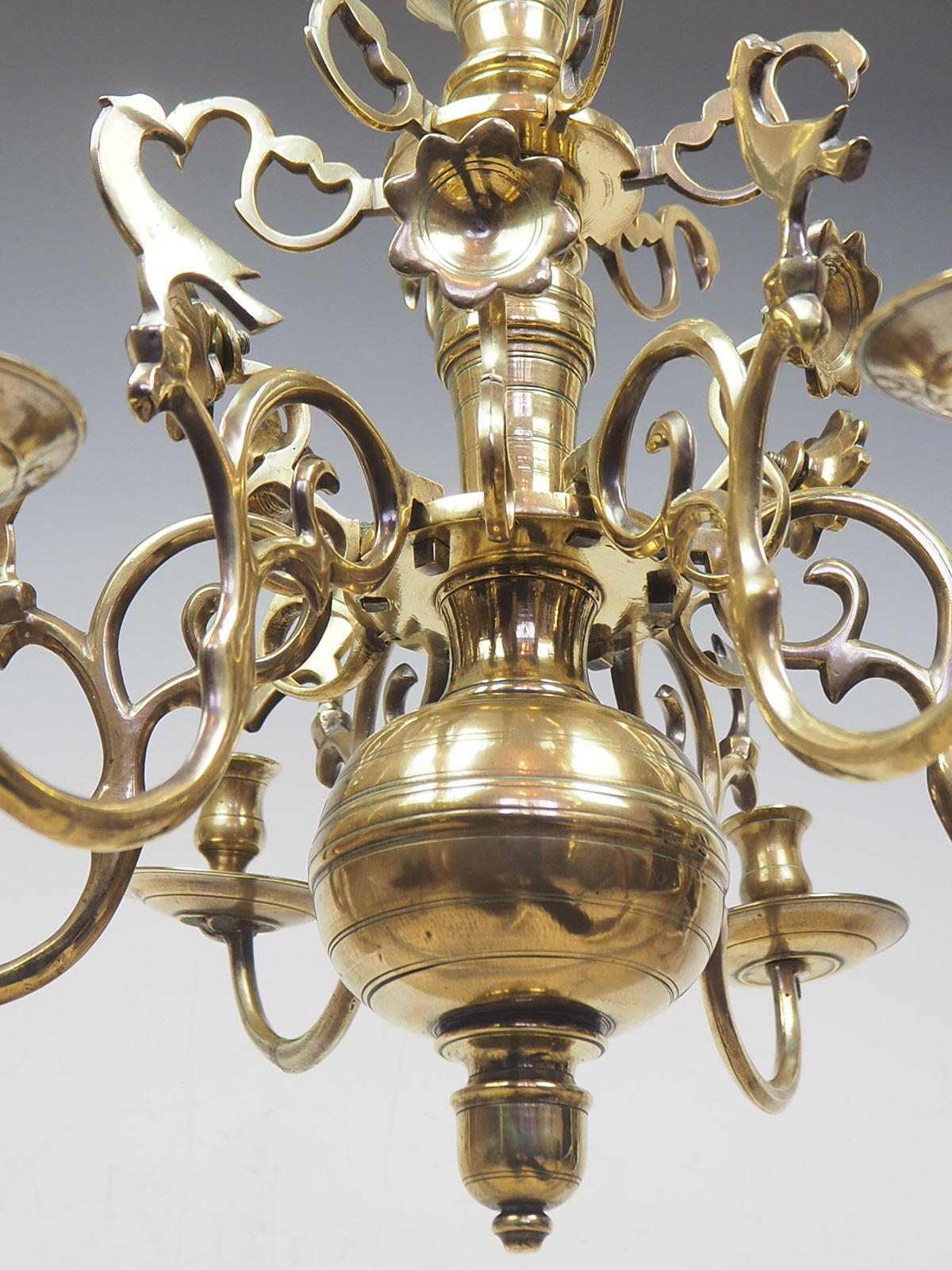 A Stunning Flemish Brass Chandelier

The central stem surmounted by a trefoil suspension loop over a domed ceiling rose, the baluster, knopped and ringed stem with decorative borders of stamped circles, with a dot numbered disc issuing eight