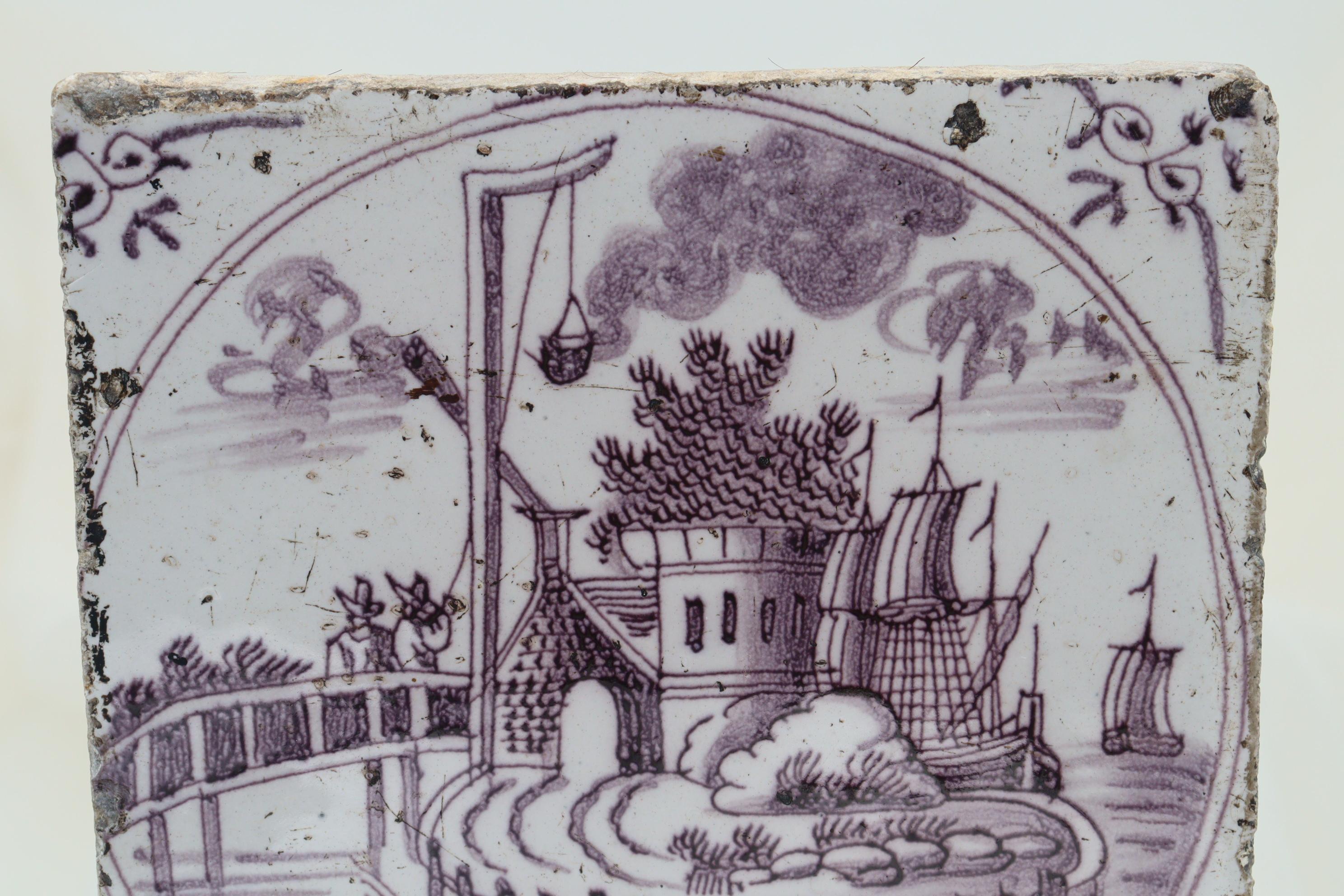 Enclosed in a circle and painted in purple or puce, the central decoration of this Dutch hand painted delft tile features a ship moored next to a fortified building where two men are using a pulley to unload some cargo. Possibly from Haarlem, the