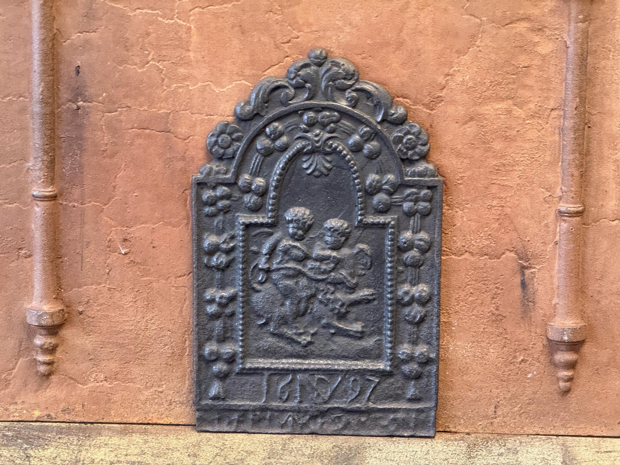 17th Century Dutch Louis XIV Period fireback with two cupids on a lion.

The fireback is made of cast iron and has a black/pewter patina. The condition is good, no cracks.