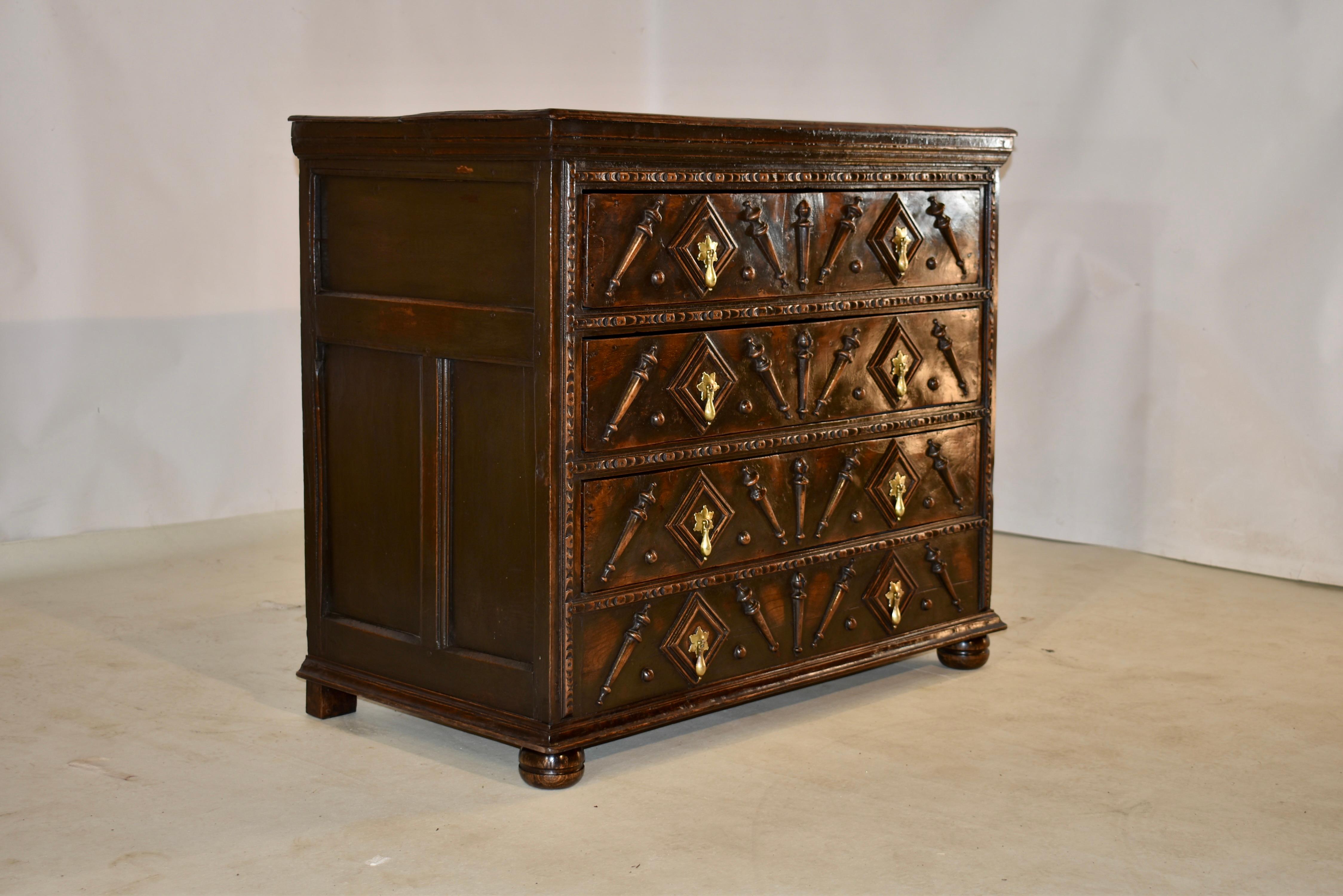 17th century period Charles II chest of drawers from England made from oak. The top is made from two planks and has a beveled edge, following down to hand paneled sides and four drawers in the front. the drawer fronts are decorated with applied half