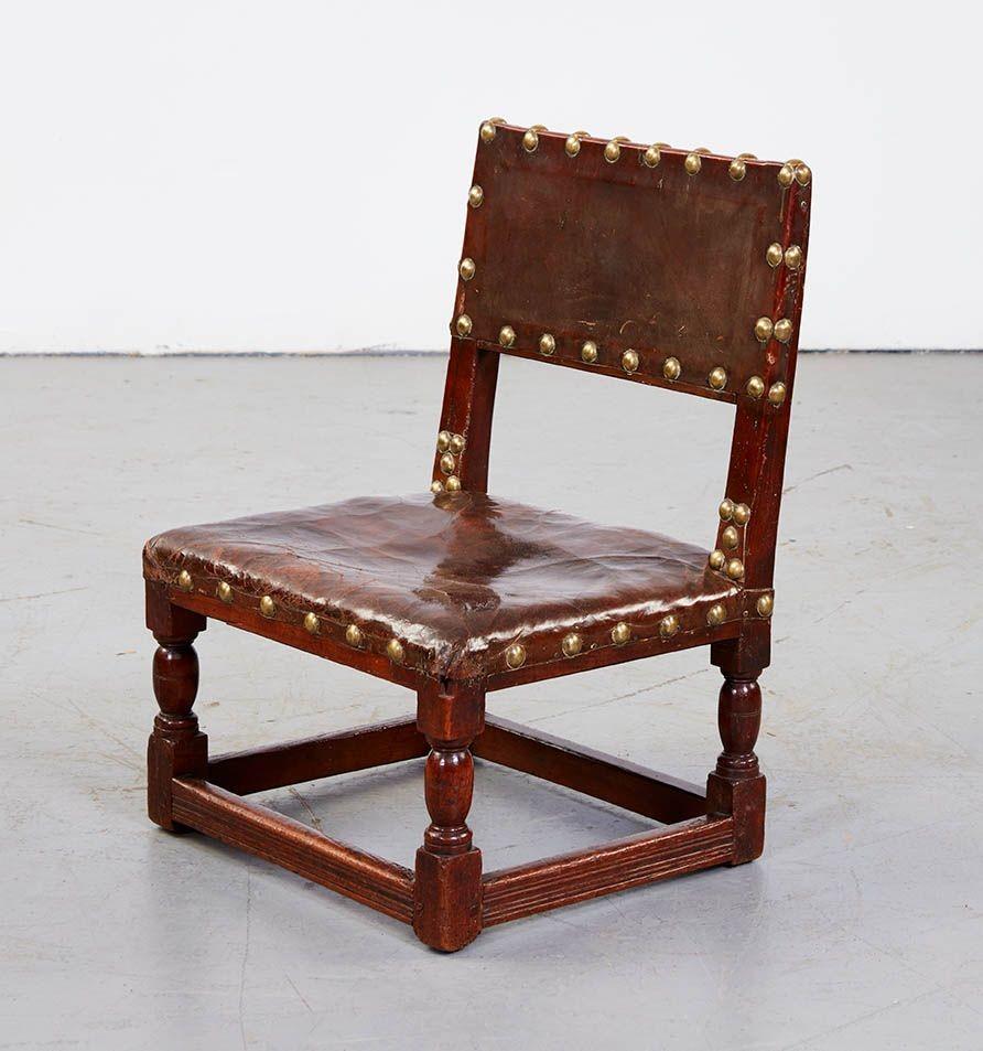 Rare low 17th century leather upholstered oak child's chair with brass studwork on turned legs joined by stretcher base, excellent color.
