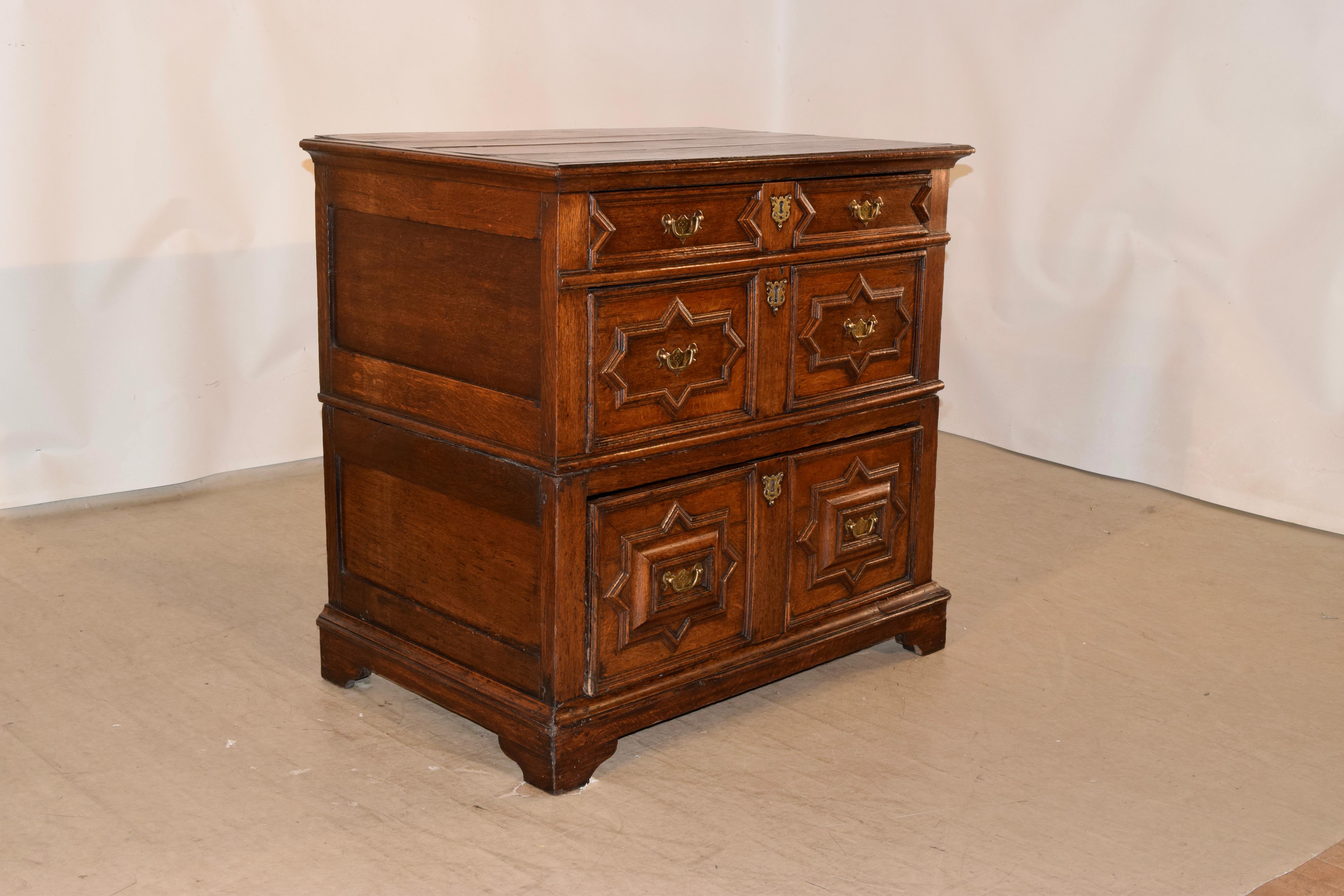 17th century rare English oak two piece chest. The top is made from four planks and is banded with a beveled edge. The sides are paneled and there are graduated drawers with geometric moldings on the drawer fronts, in differing patterns for added