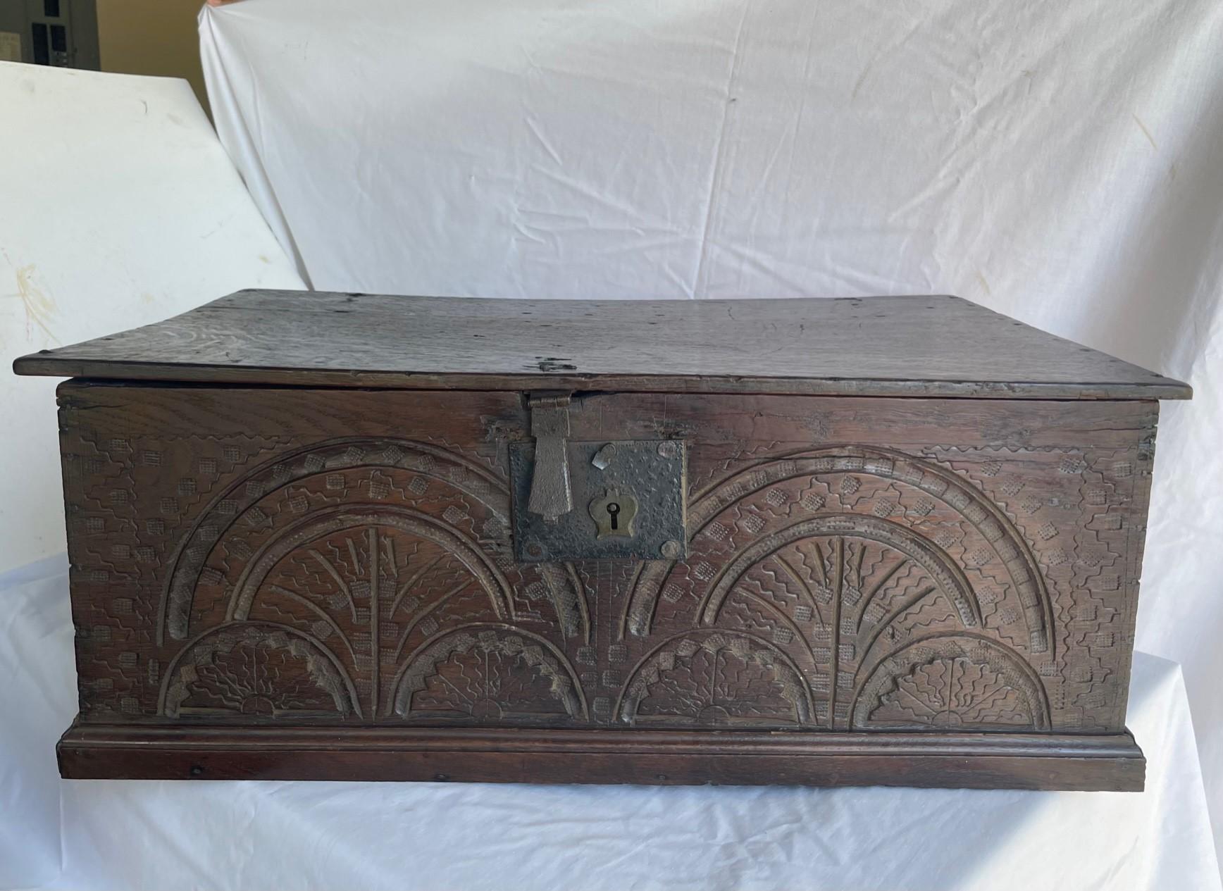 17th Century English Jacobean Carved Oak Bible Box.

Period Jacobean solid dark oak bible box from the 17th century. The front is beautifully carved with a lunette design. Wrought iron rattail hinges, latch and lock plate are original. Lock is