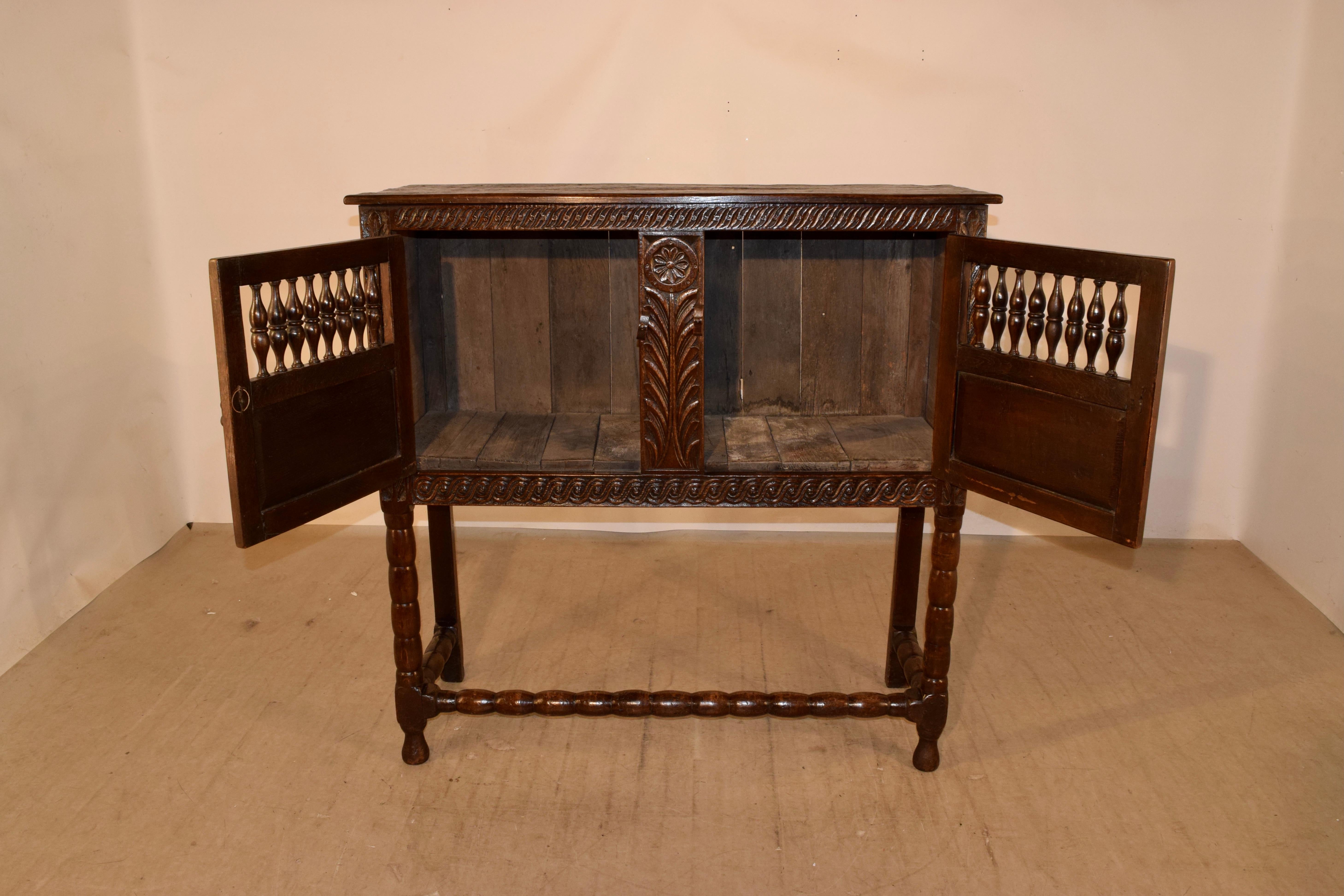 17th century oak aubrey food cupboard from England. The top is simple and has pegged construction, following down to simply paneled sides and two wonderfully hand carved doors, which open to reveal storage. The piece is supported on hand turned